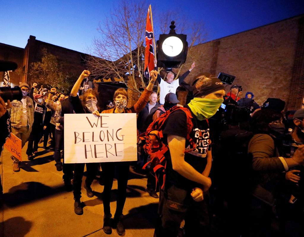 Demonstrators marching for voting rights pass supporters of U.S. President Donald Trump carrying Confederate flags in Graham, North Carolina, U.S., November 3, 2020.   REUTERS/Jonathan Drake