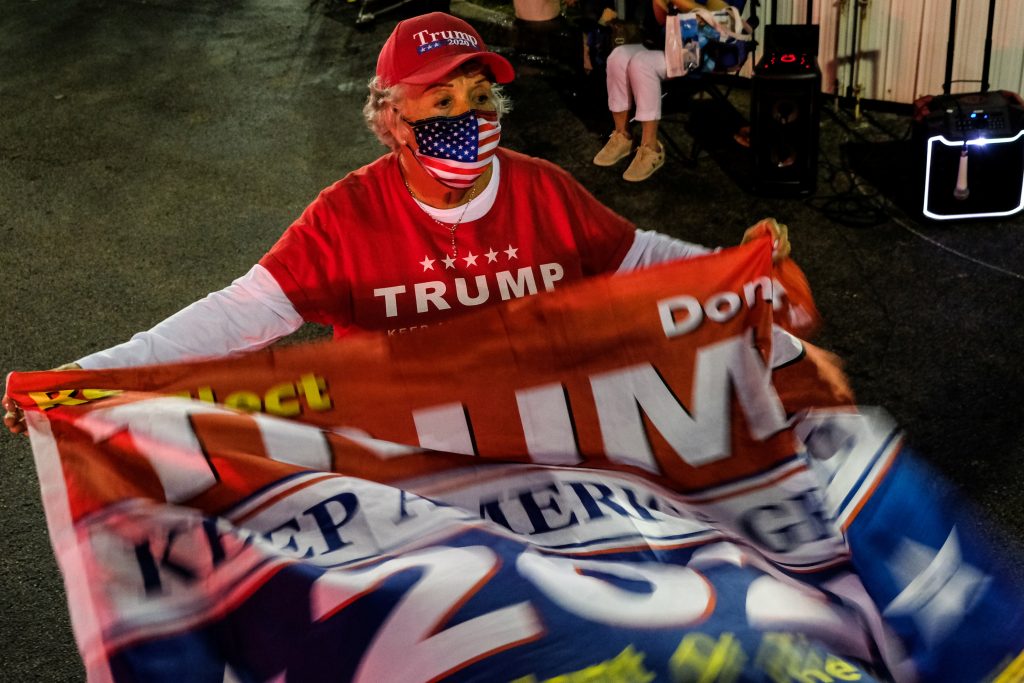 A Trump supporter waves a flag outside John F. Kennedy Library, a Miami-Dade County polling station, during the 2020 U.S. presidential election in Miami, Florida, U.S. November 3, 2020.  REUTERS/Maria Alejandra Cardona