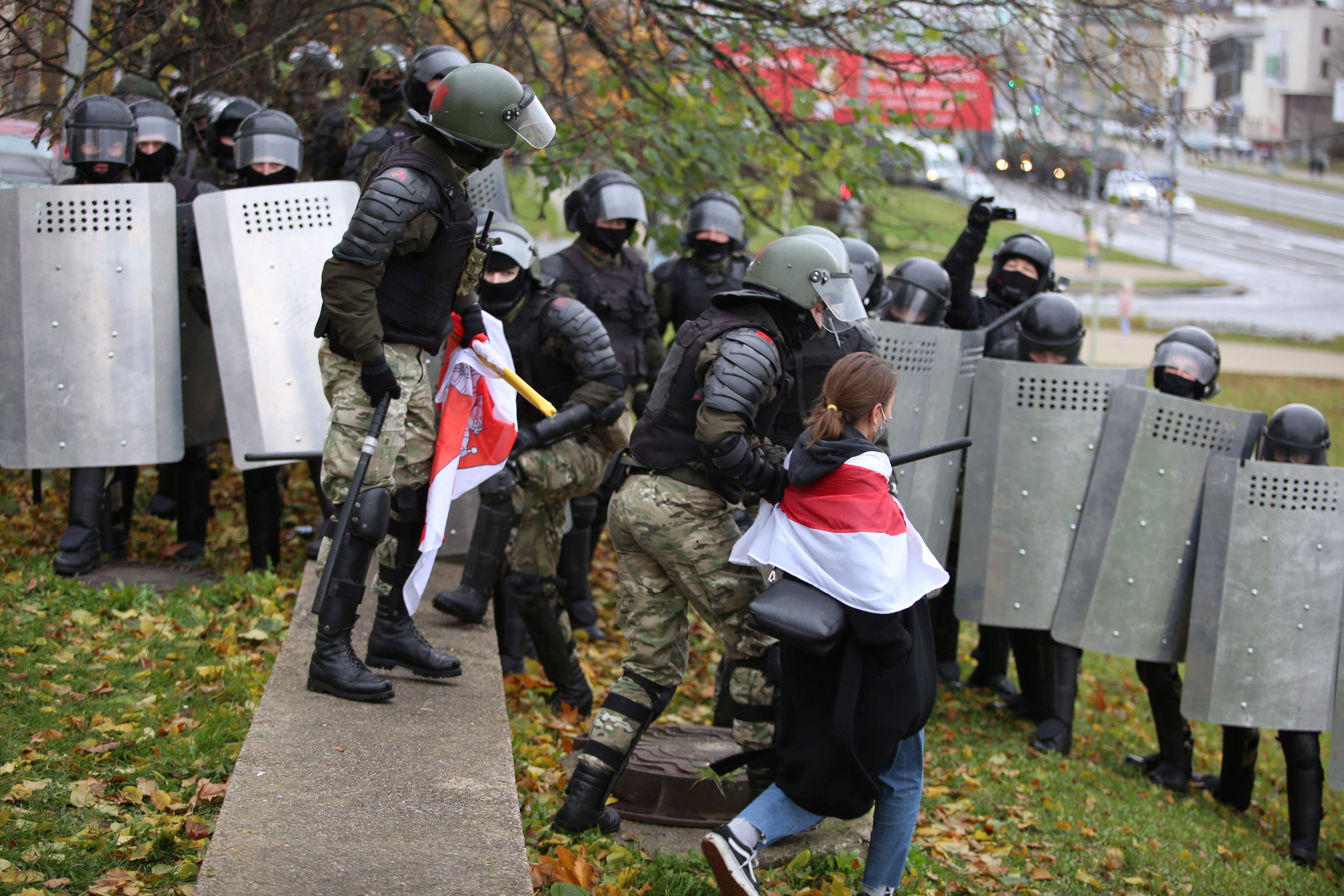 A woman wearing a historical white-red-white flag of Belarus is taken away by a law enforcement officer during a rally to reject the presidential election results in Minsk, Belarus November 8, 2020. REUTERS/Stringer