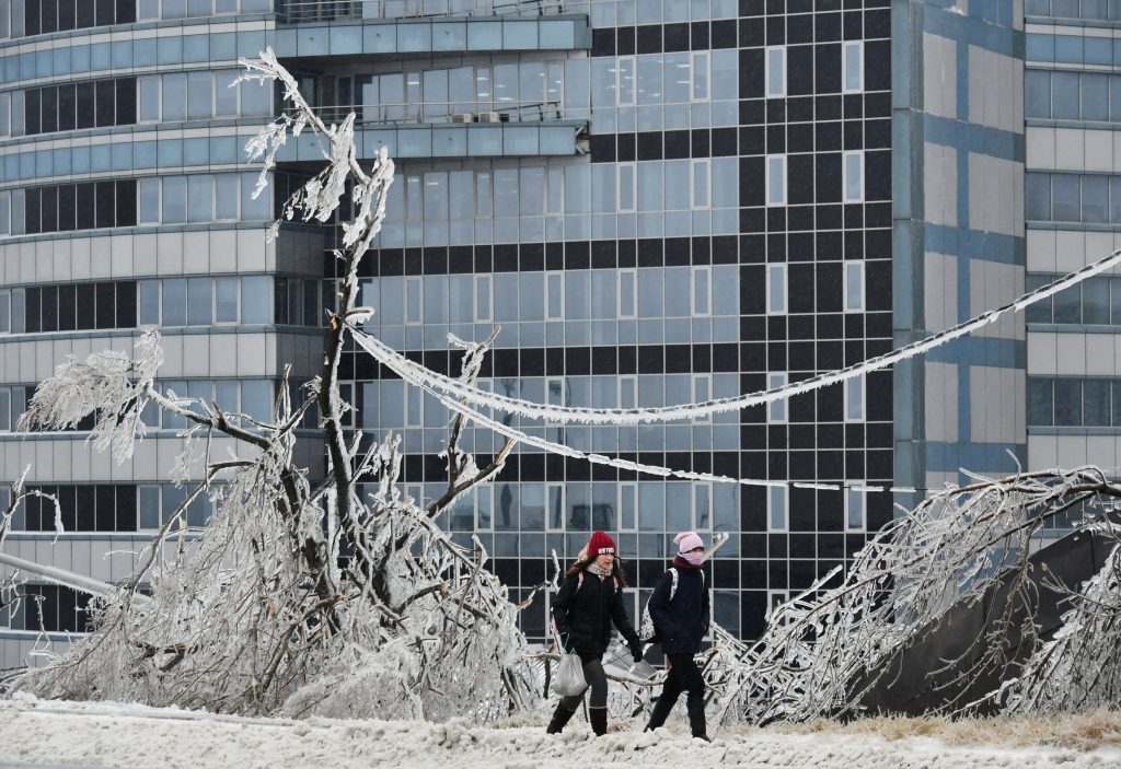 People walk past trees covered with ice after freezing rain in the far eastern city of Vladivostok, Russia November 19, 2020. REUTERS/Yuri Maltsev