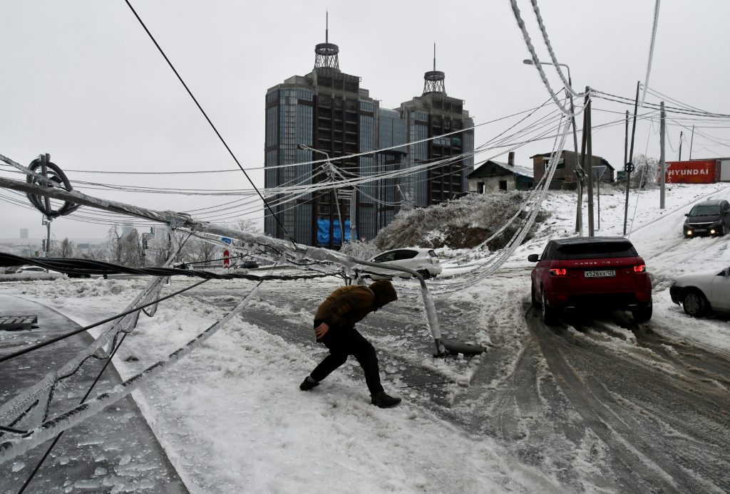 FILE PHOTO: A man walks under a damaged power pole covered with ice after freezing rain in the far eastern city of Vladivostok, Russia, November 19, 2020. REUTERS/Yuri Maltsev/File Photo