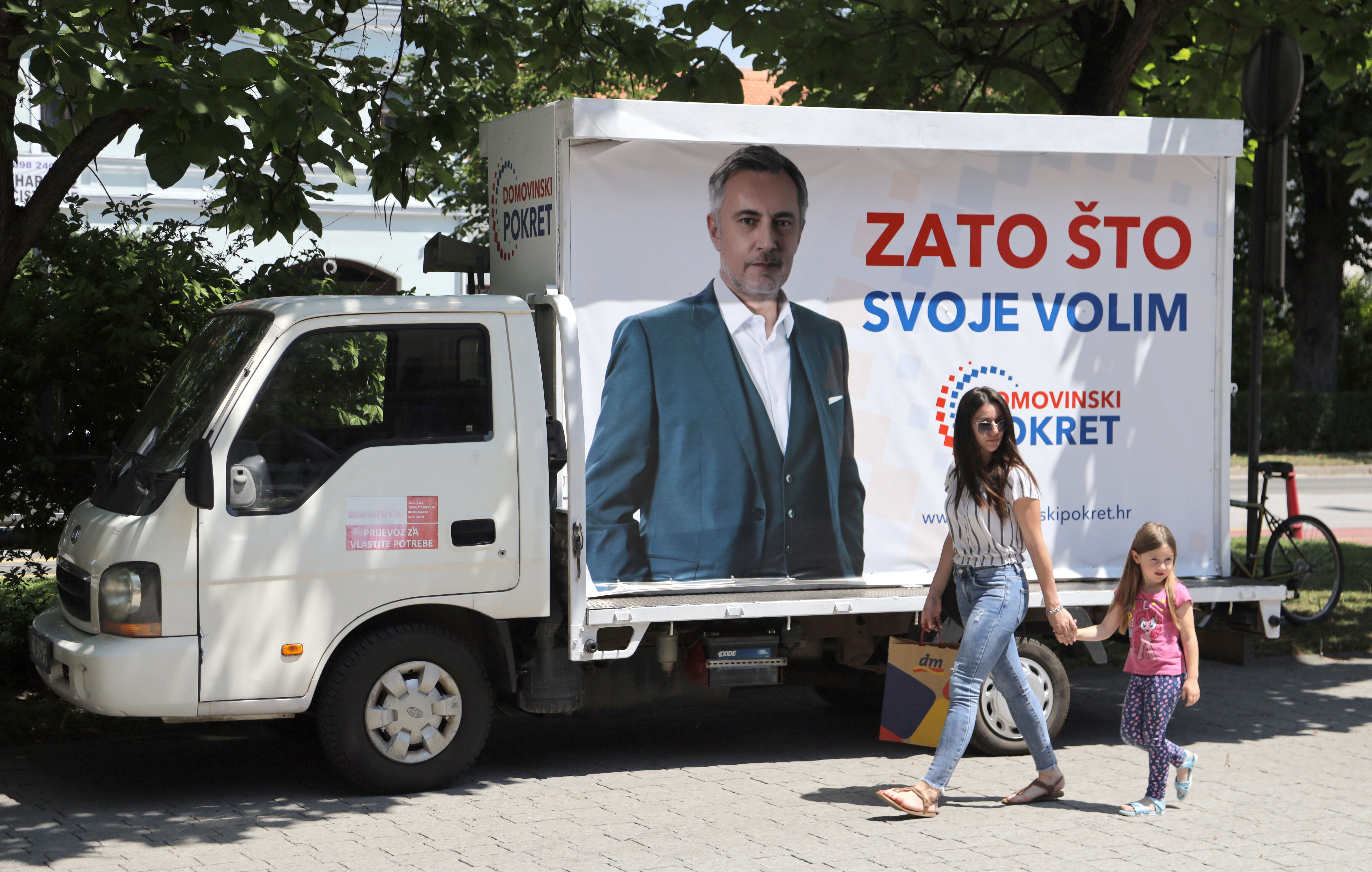 Izbori Hrvatska A woman with a child walks next to a truck with an election poster picturing Miroslav Skoro, leader of the Homeland Movement party, in Velika Gorica, Croatia, June 30, 2020. REUTERS/Antonio Bronic