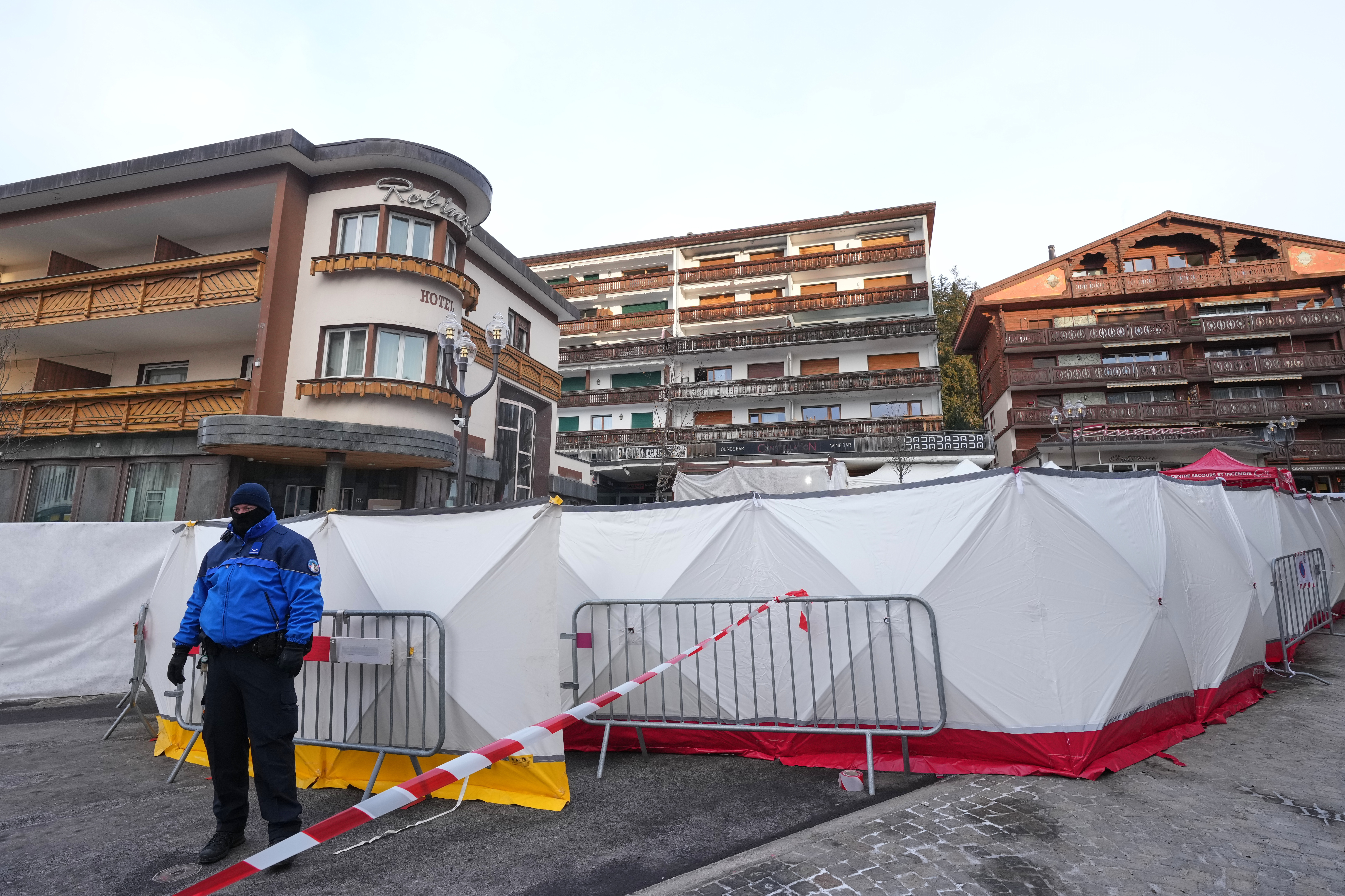 Security stands in front of the sealed off Le Constellation bar, where a devastating fire left dead and injured during the New Year's celebrations in Crans-Montana, Swiss Alps, Switzerland, Friday morning, Jan. 2, 2026. (AP Photo/ Antonio Calanni)