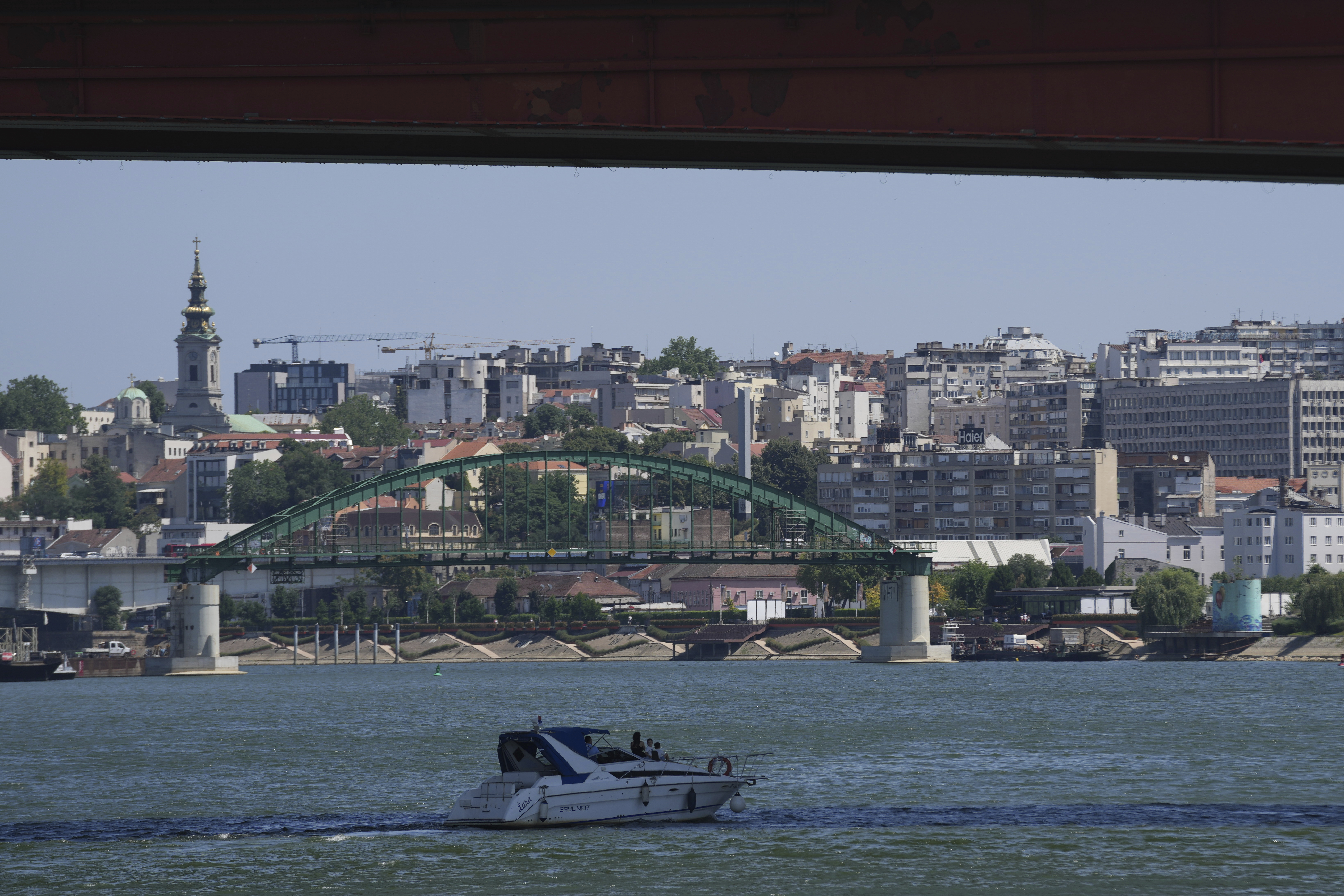 A boat float in shadow under the Gazela (Gazelle) bridge at Sava river in Belgrade, Serbia, Friday, June 20, 2025. (AP Photo/Darko Vojinovic)
