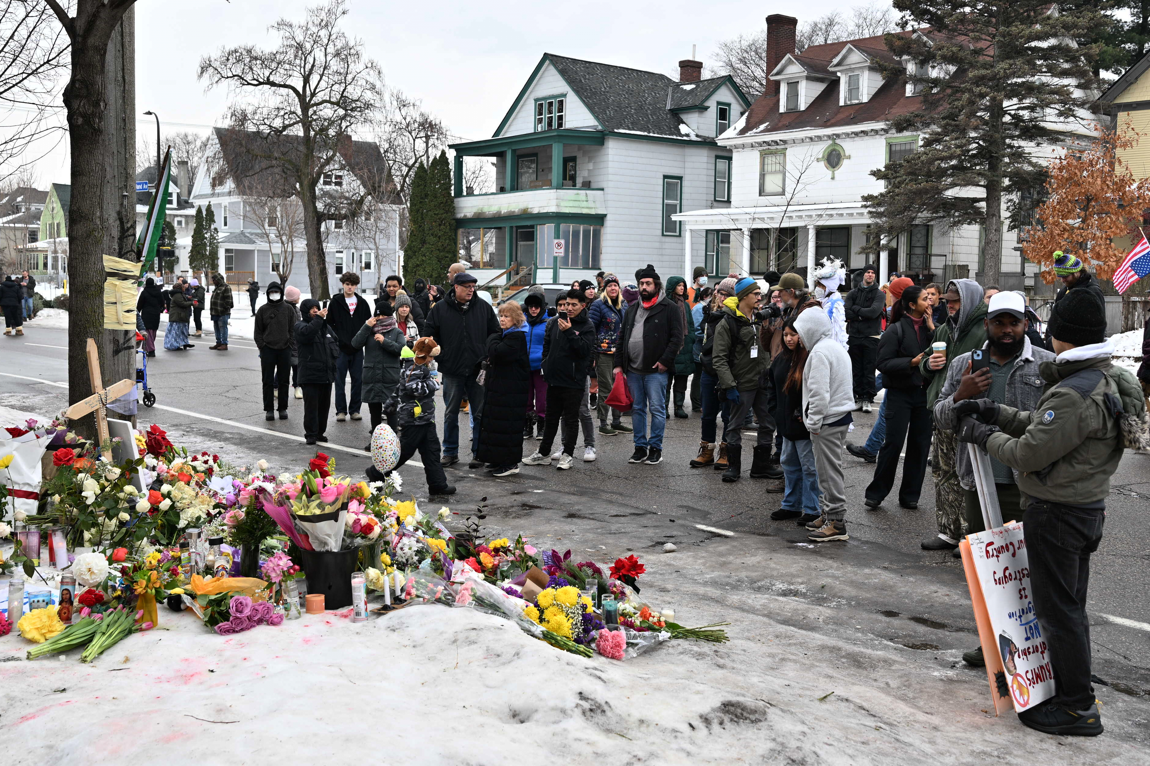 People gather around a makeshift memorial honoring the victim of a fatal shooting involving federal law enforcement agents, inear the site of the shooting, Thursday, Jan. 8, 2026, in Minneapolis. (AP Photo/Tom Baker)