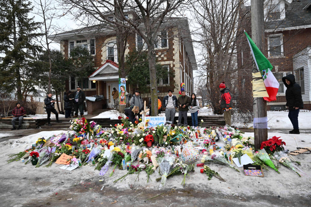 People gather around a makeshift memorial honoring the victim of a fatal shooting involving federal law enforcement agents, inear the site of the shooting, Thursday, Jan. 8, 2026, in Minneapolis. (AP Photo/Tom Baker)