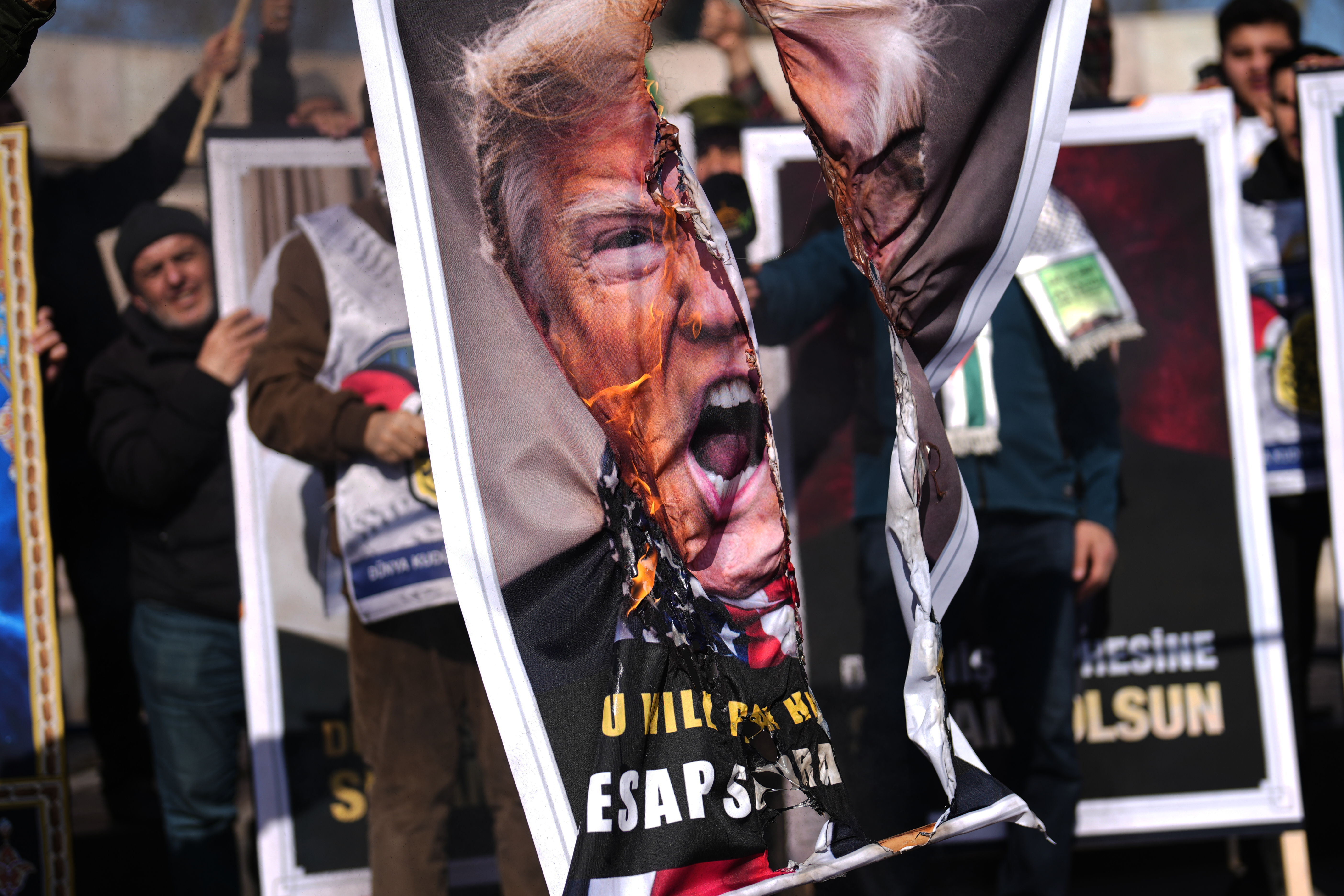 People burn a photograph of U.S. President Donald Trump during a protest against Israel and the U.S., in Istanbul, Friday, March 13, 2026. (AP Photo/Francisco Seco)