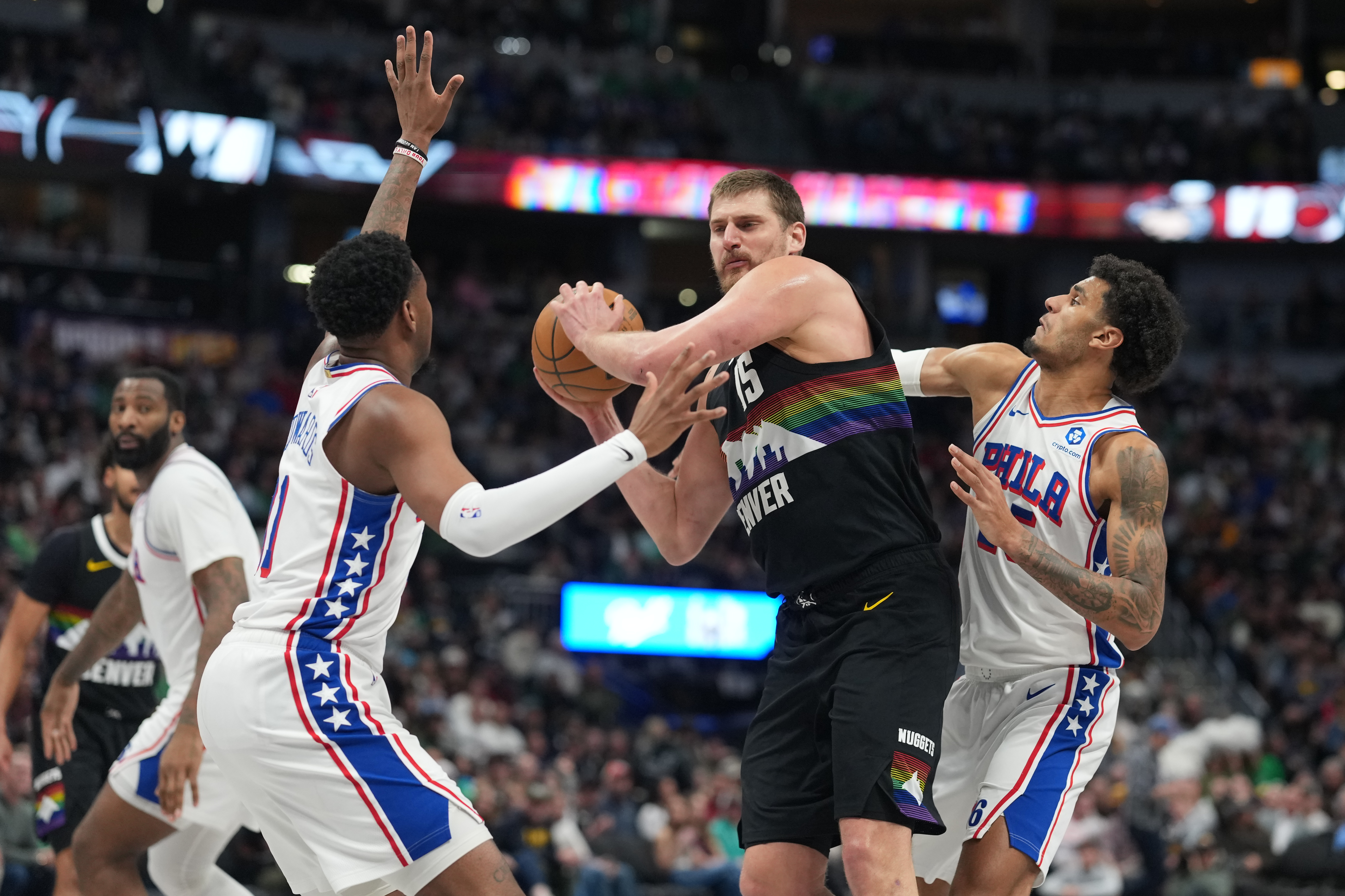 Denver Nuggets center Nikola Jokić looks to pass the ball as Philadelphia 76ers forwards Justin Edwards, left, and Dominick Barlow defend in the second half of an NBA basketball game Tuesday, March 17, 2026, in Denver. (AP Photo/David Zalubowski)