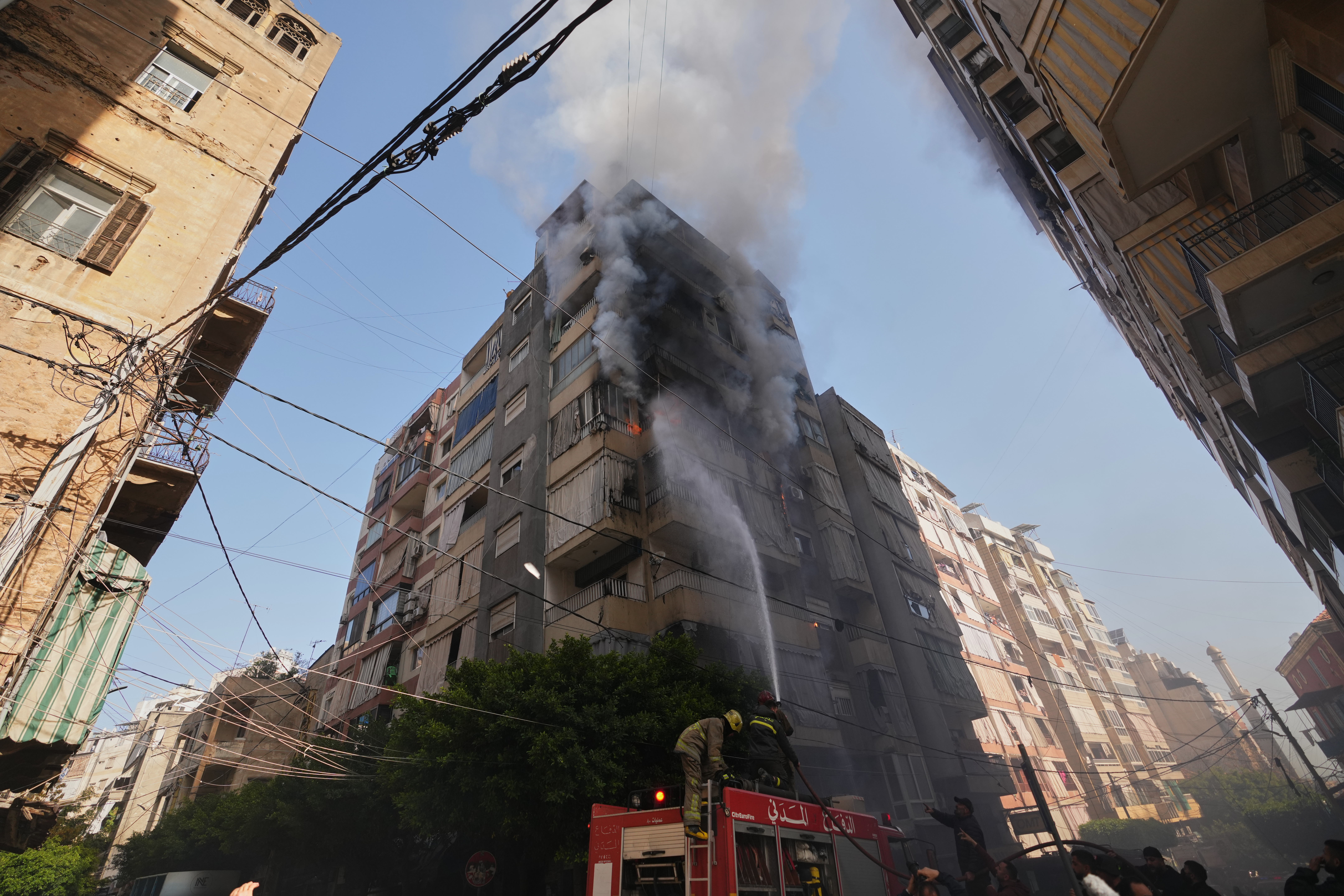 Firefighters spray water on a burning residential building following an Israeli airstrike
