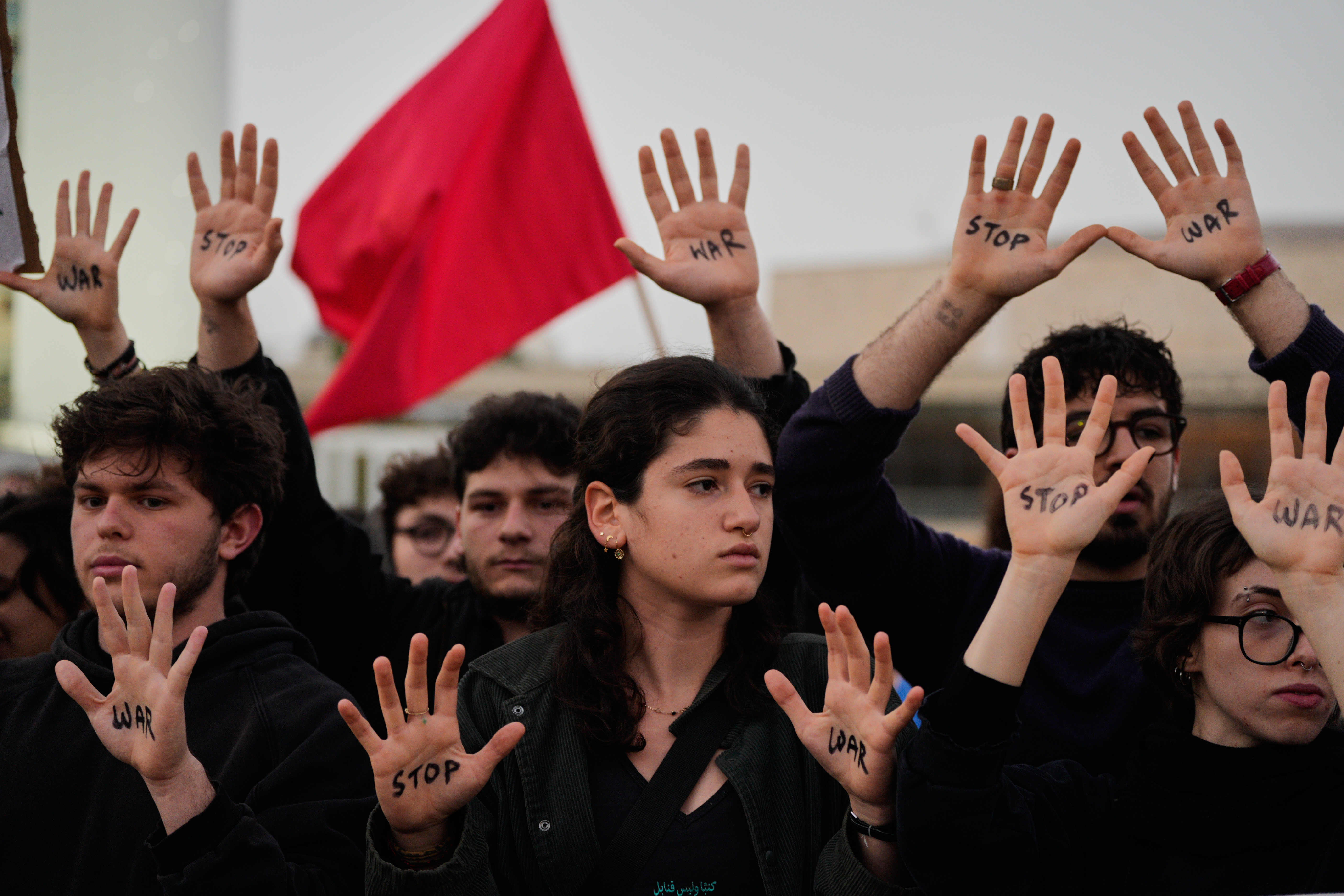 People raise their hands during a protest calling for an end to the war in Tel Aviv