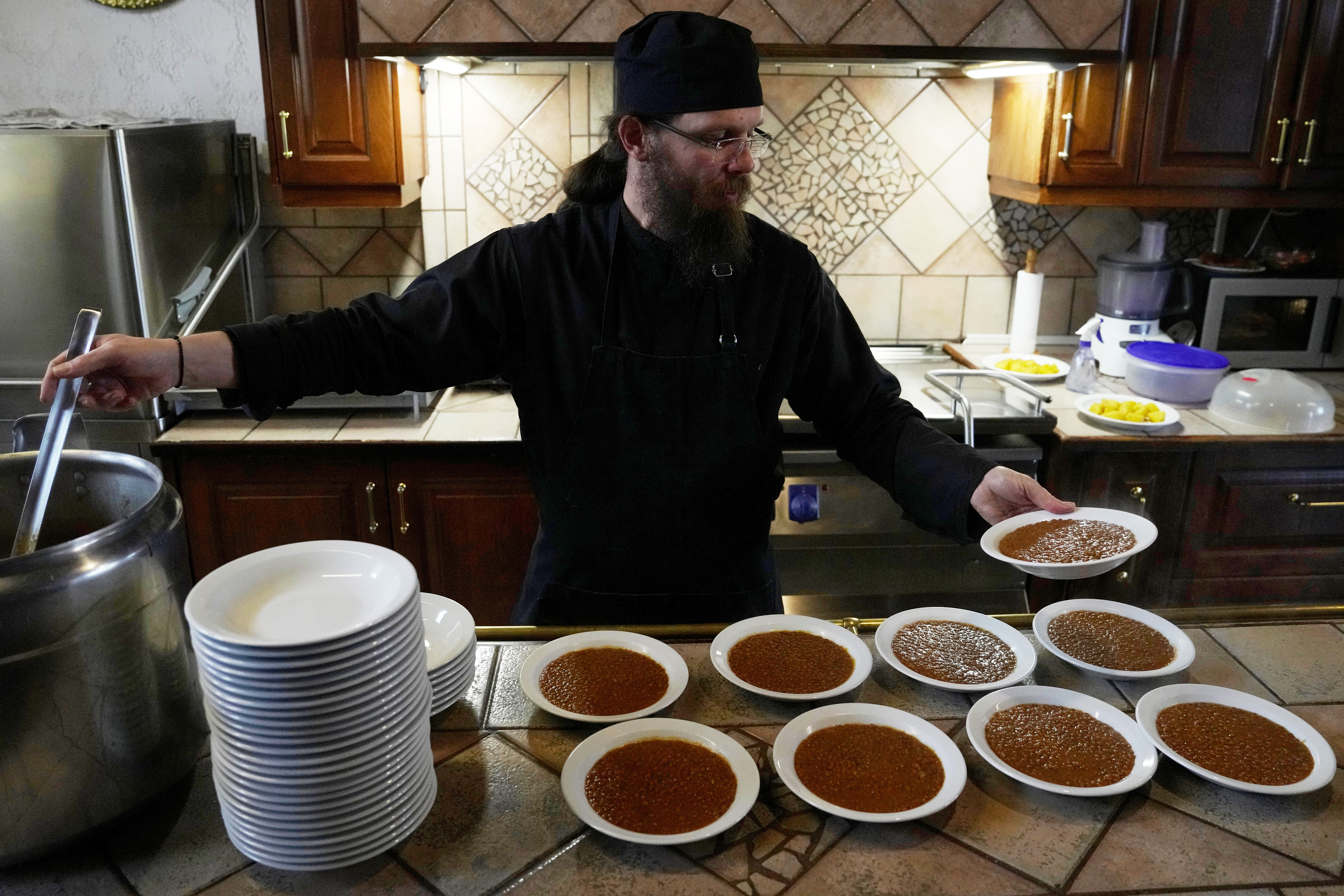 Father Isaac serves lentils for the midday meal at the Monastery of St. Augustine and Seraphim of Sarov in the village of Trikorfo, about 236 kilometers (147 miles) northwest of Athens, Friday, March 20, 2026. (AP Photo/Thanassis Stavrakis)