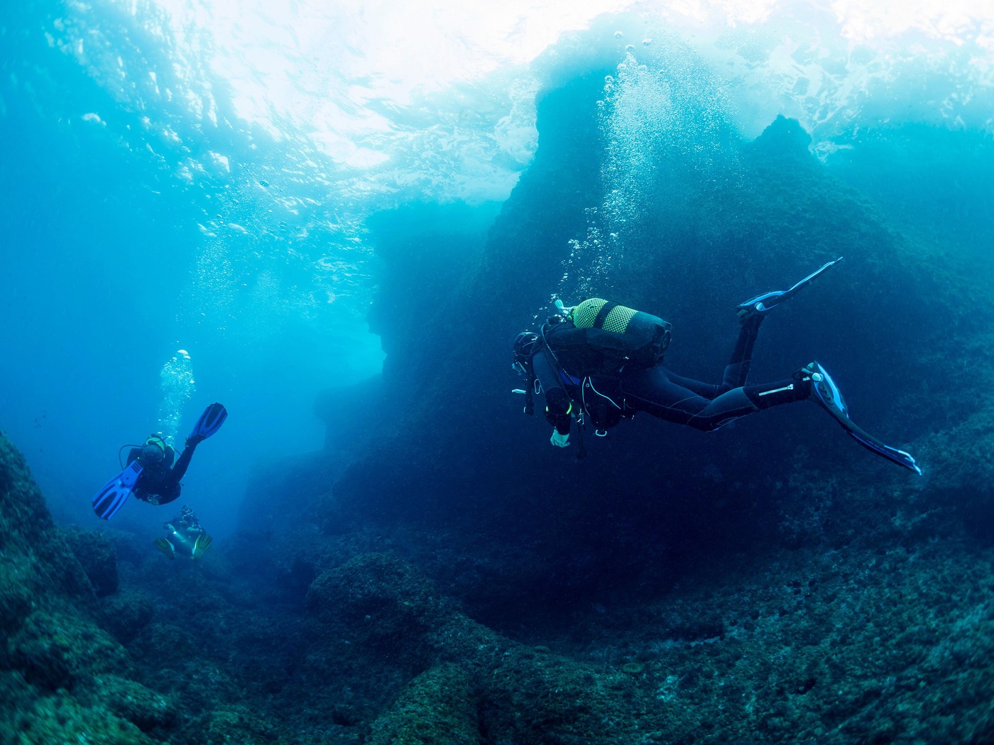 divers diving with sun reflecting on sea surface