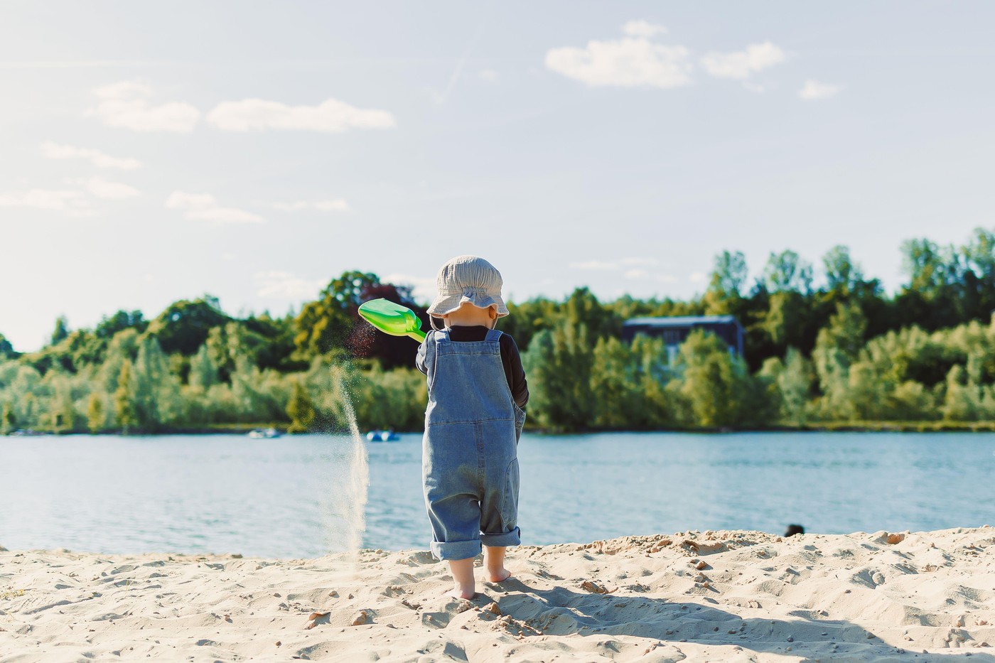 Happy 2 year old little boy playing on sand during summer vacation, wearing hat. Family travel and vacation, outdoor activities on summer beach holida