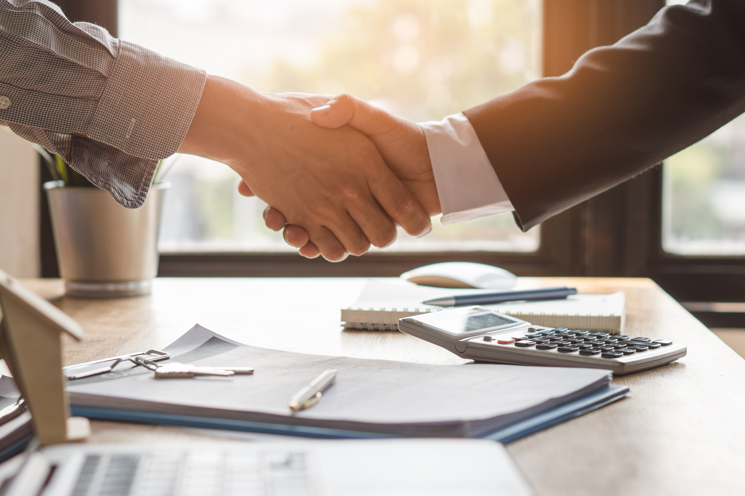 nejtiv za biznis    Top view hands of agent and client shaking hands after signed contract buy new apartment.