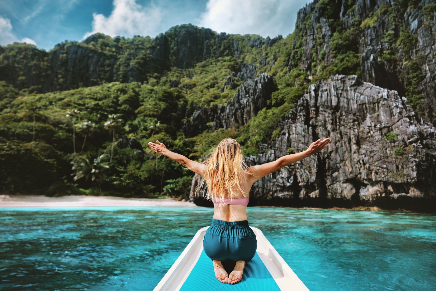 Woman tourist traveling in Philippines, girl happy raised hands on the boat island hopping tour enjoying sea and mountains view active summer vacation