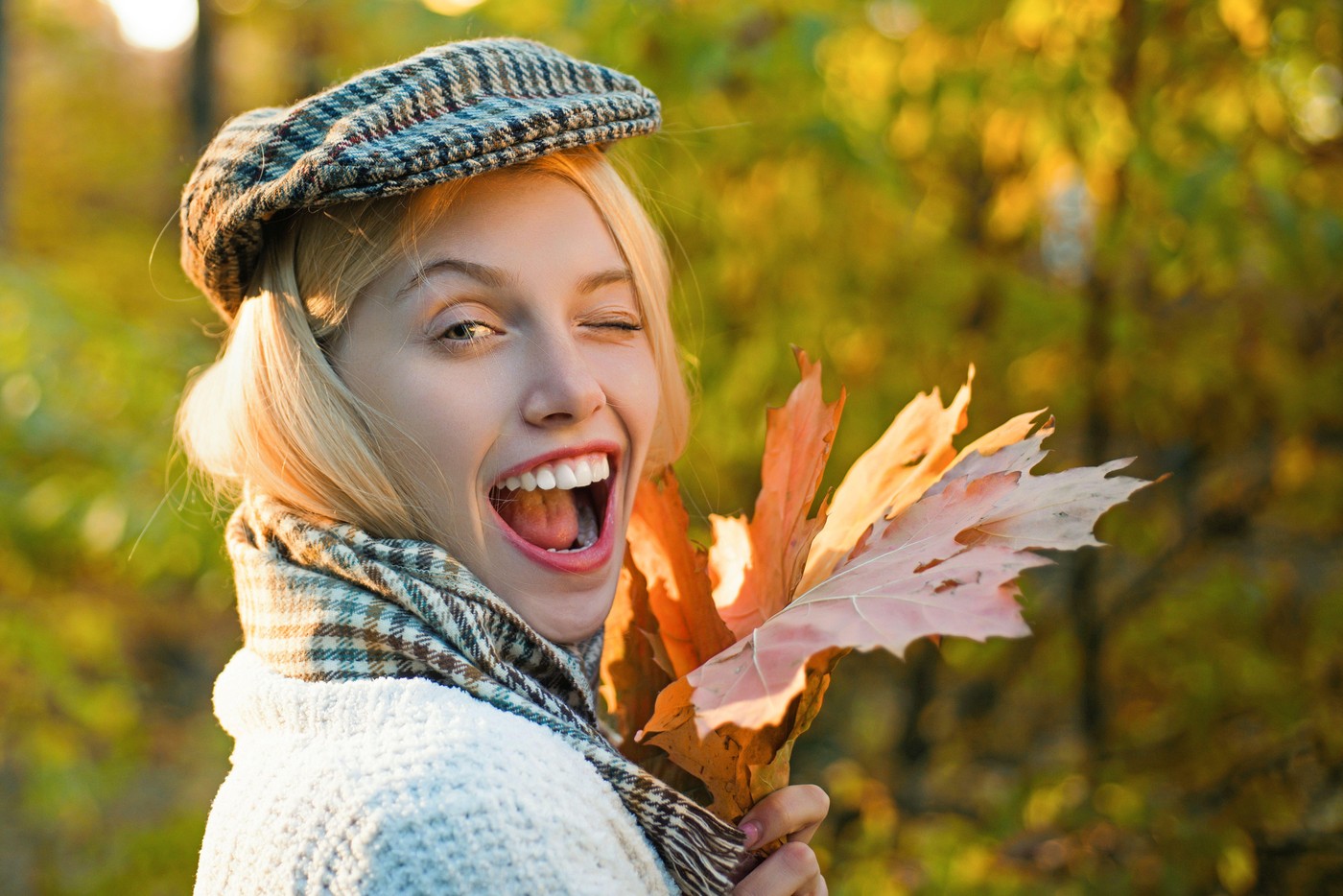 Autumn woman with fall yellow maple leaf near face, outdoor portrait. Girl with autumn leaves. Portrait of beautiful young woman outdoors in autumn