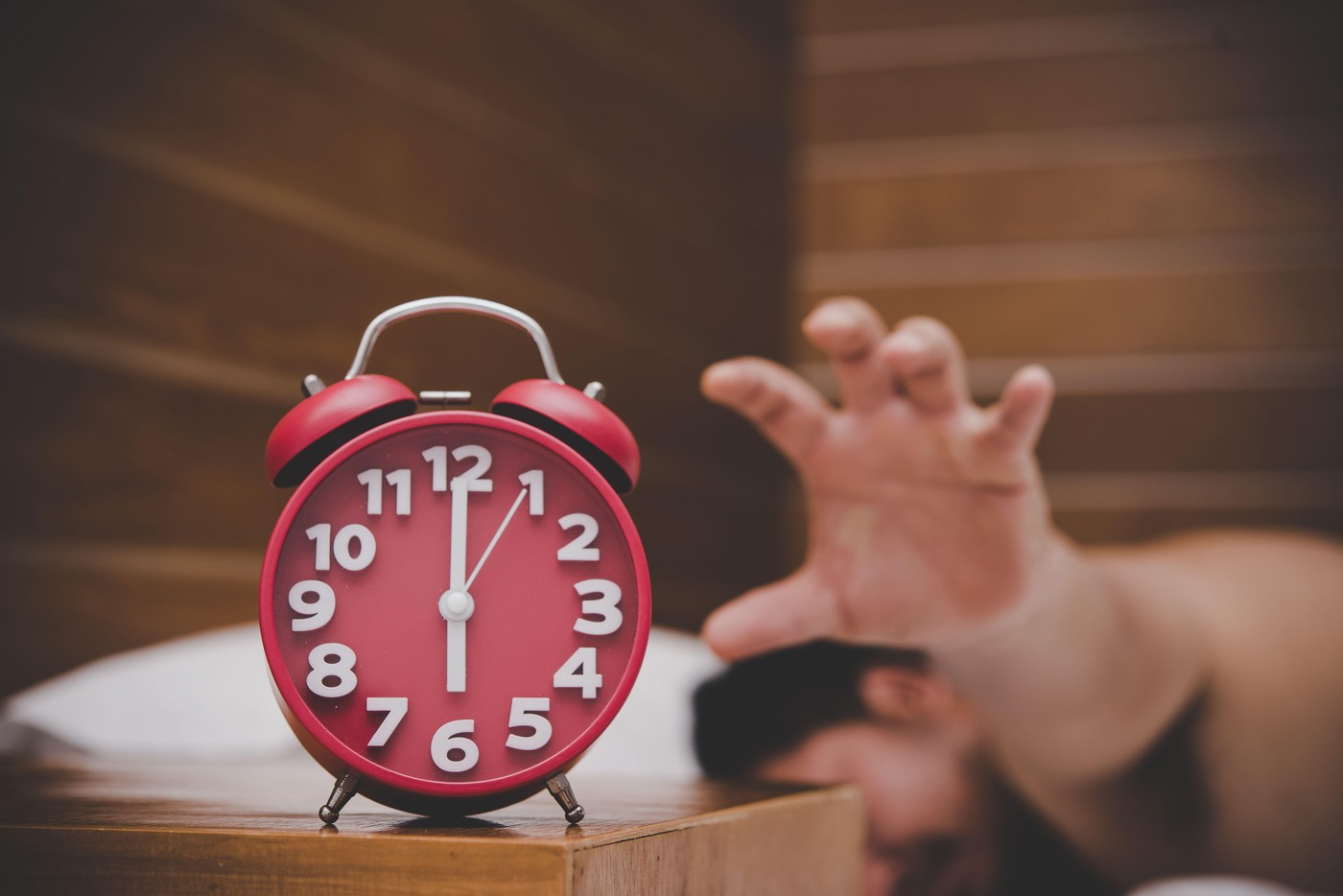 Man being awakened by an alarm clock in his bedroom.