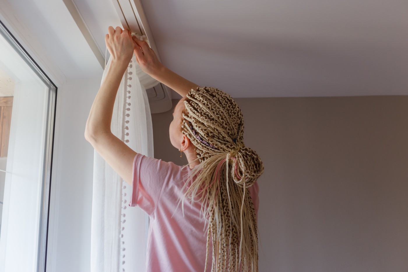 Woman hanging up curtains at the window