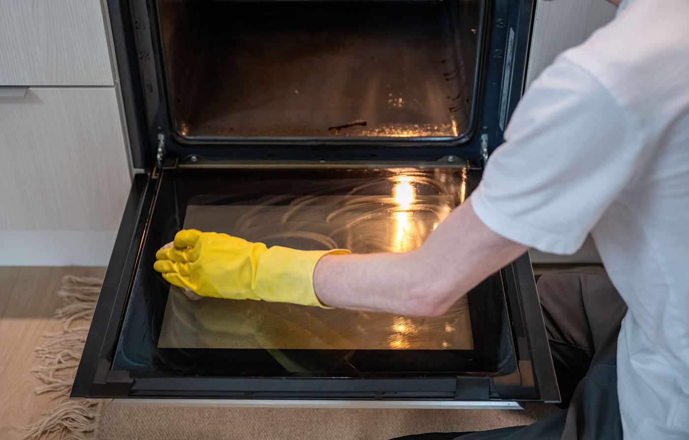 Person cleaning oven door glass with sponge with yellow rubber gloves. High quality photo,Image: 1025849661, License: Royalty-free, Restrictions: , Model Release: no, Credit line: Anastasiia Akhmetkabirova / Alamy / Profimedia