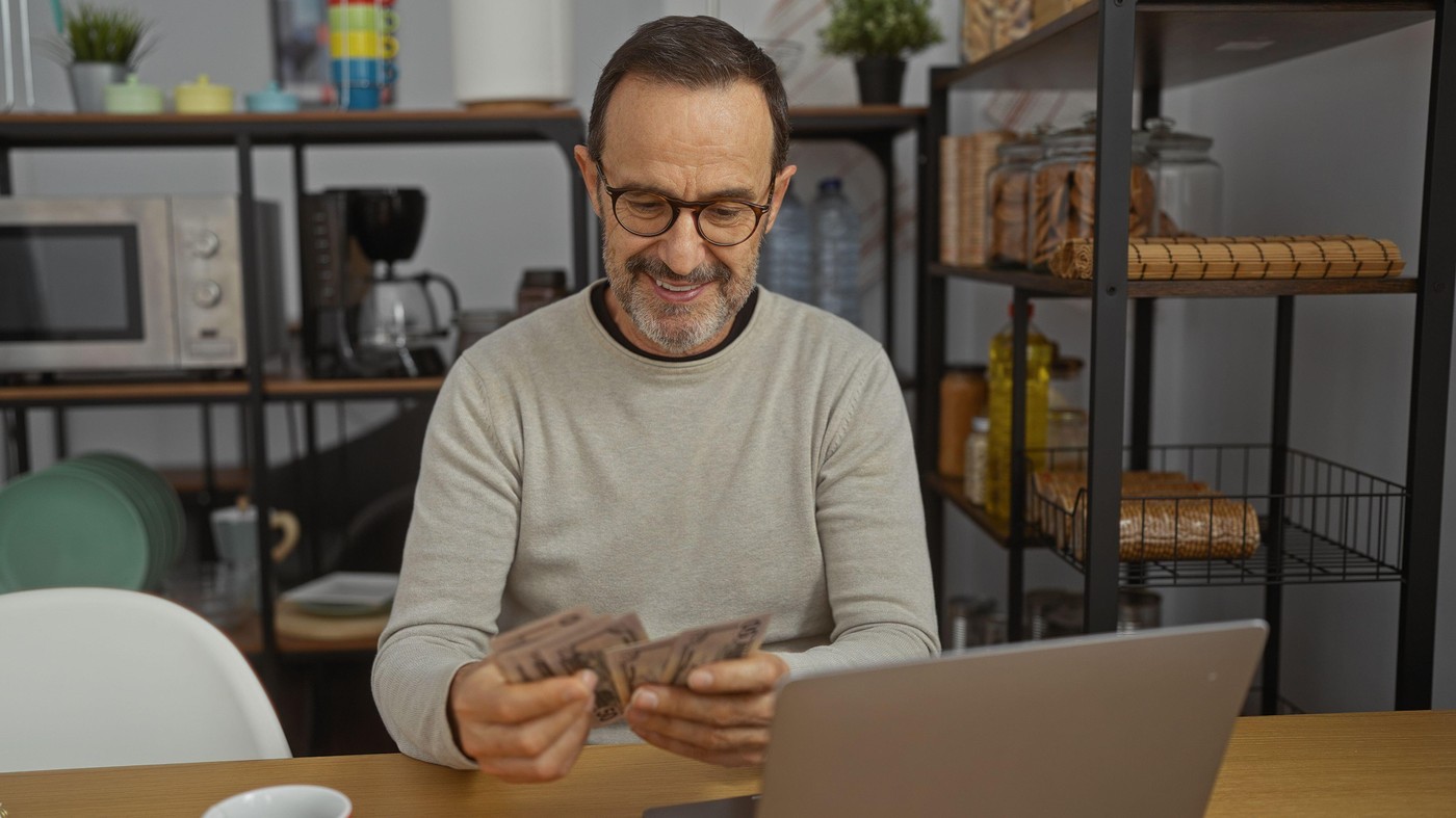 Hispanic man counting american dollars in a modern office setting, depicting a professional environment with a mature businessman managing finances in