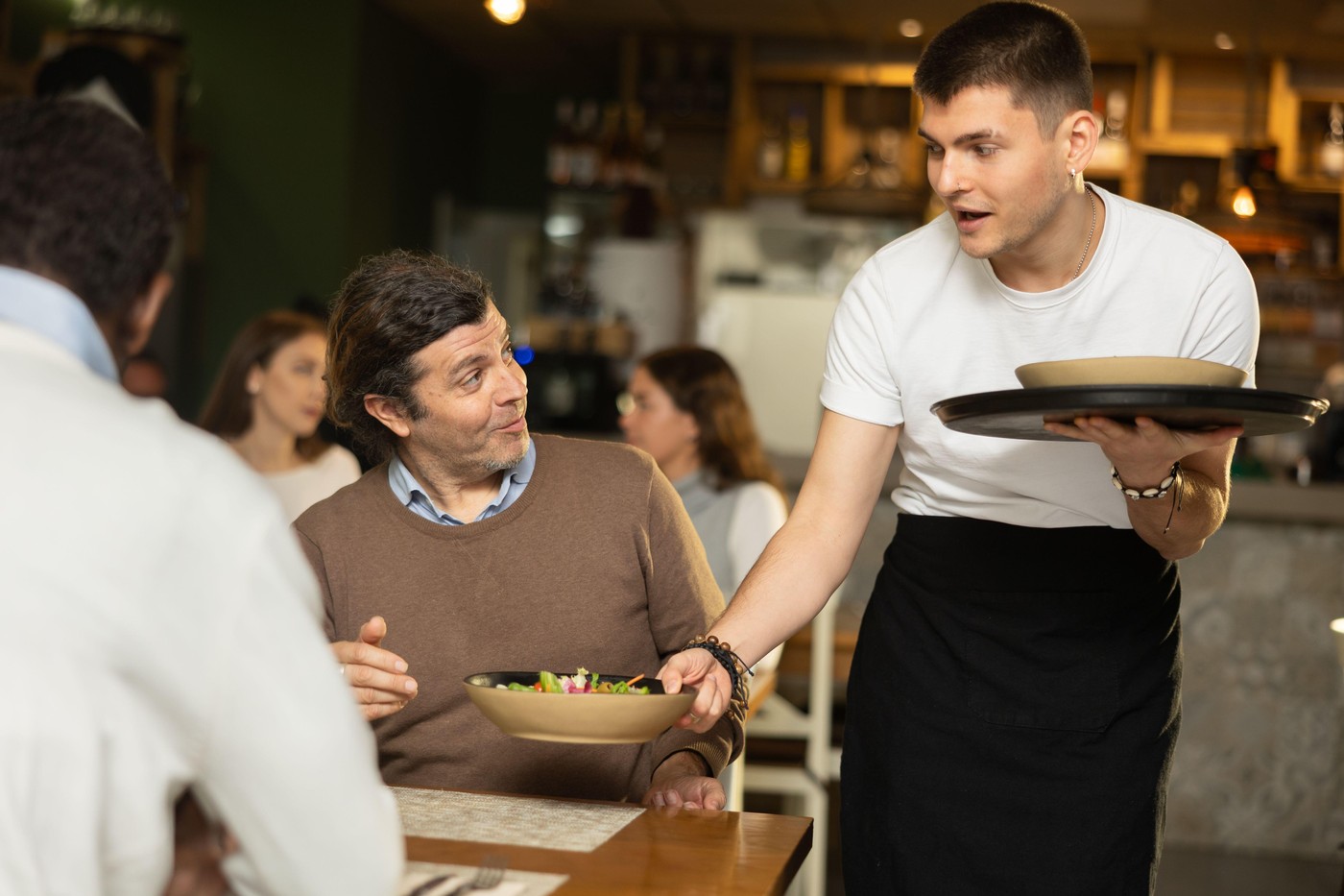 Waiter guy brings an order for men