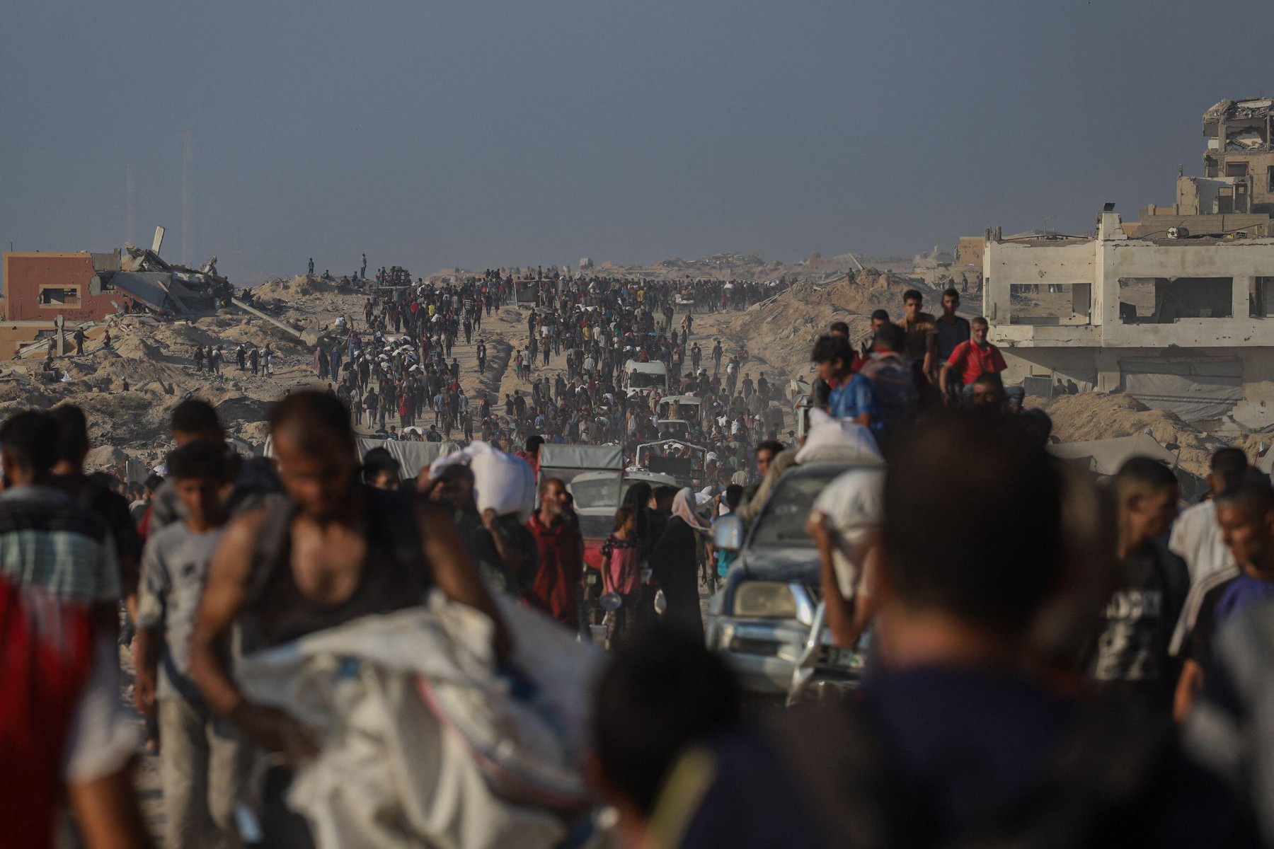 Palestinians carry humanitarian aid received through the Zikim crossing as they return to their families near the Al-Sudaniya area in northern Gaza, Palestine on July 26 2025, reflecting the ongoing humanitarian crisis in the Strip. Photo by Ramez Habboub