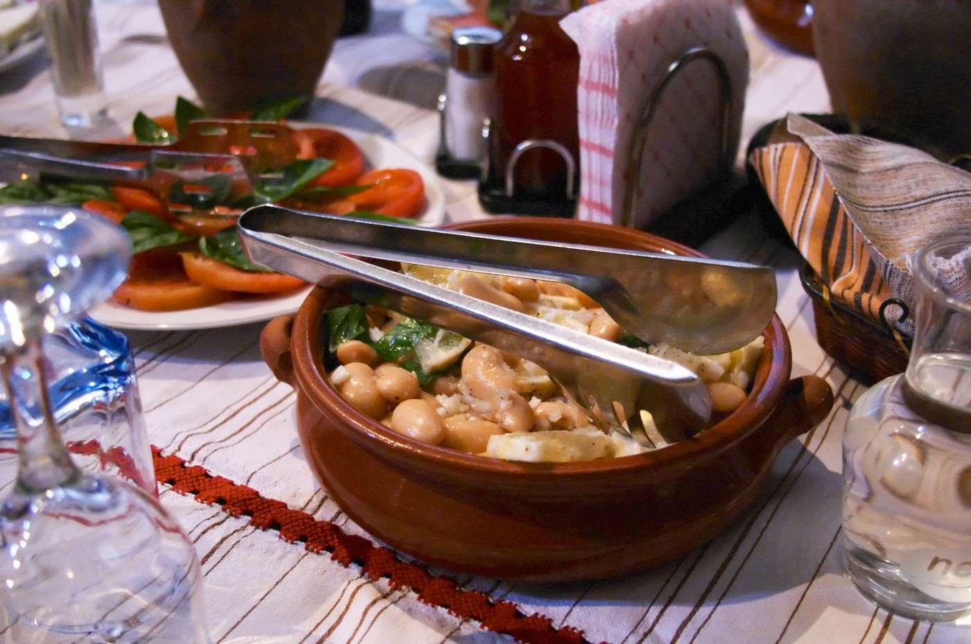 Salad with white beans in an earthenware bowl. Tomato and basil salad. White beans typical for south east Albania. Tradita traditional restaurant, Shkodra. Albania, Balkan, Europe.