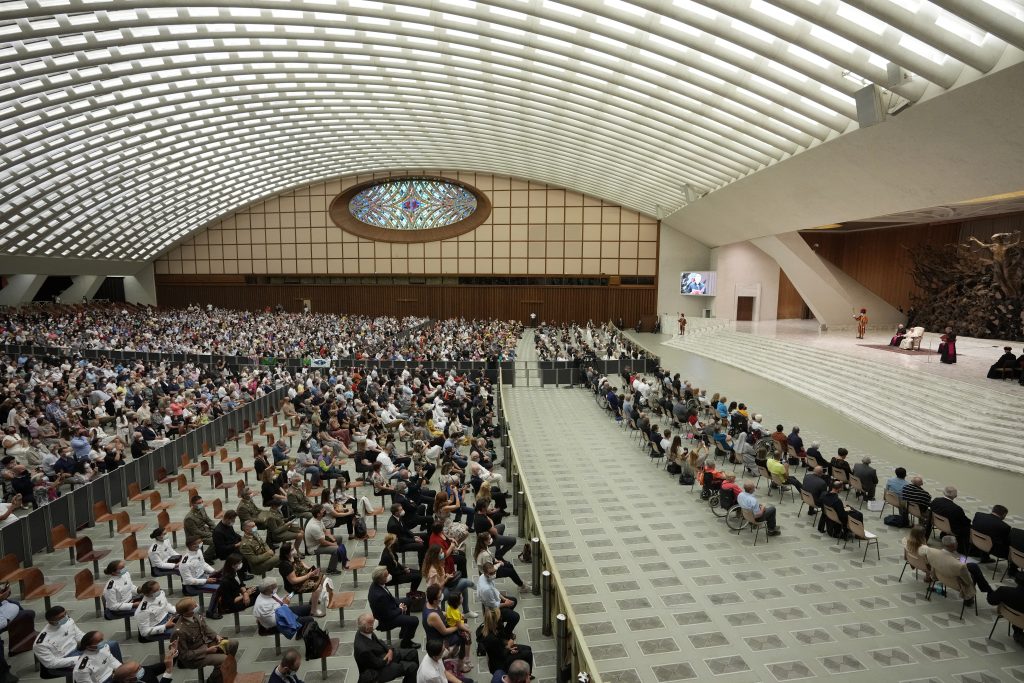 People listen to Pope Francis, white figure on stage, during his weekly general audience in Paul VI hall, at the Vatican, Wednesday, Sept. 8, 2021. (AP Photo/Andrew Medichini)