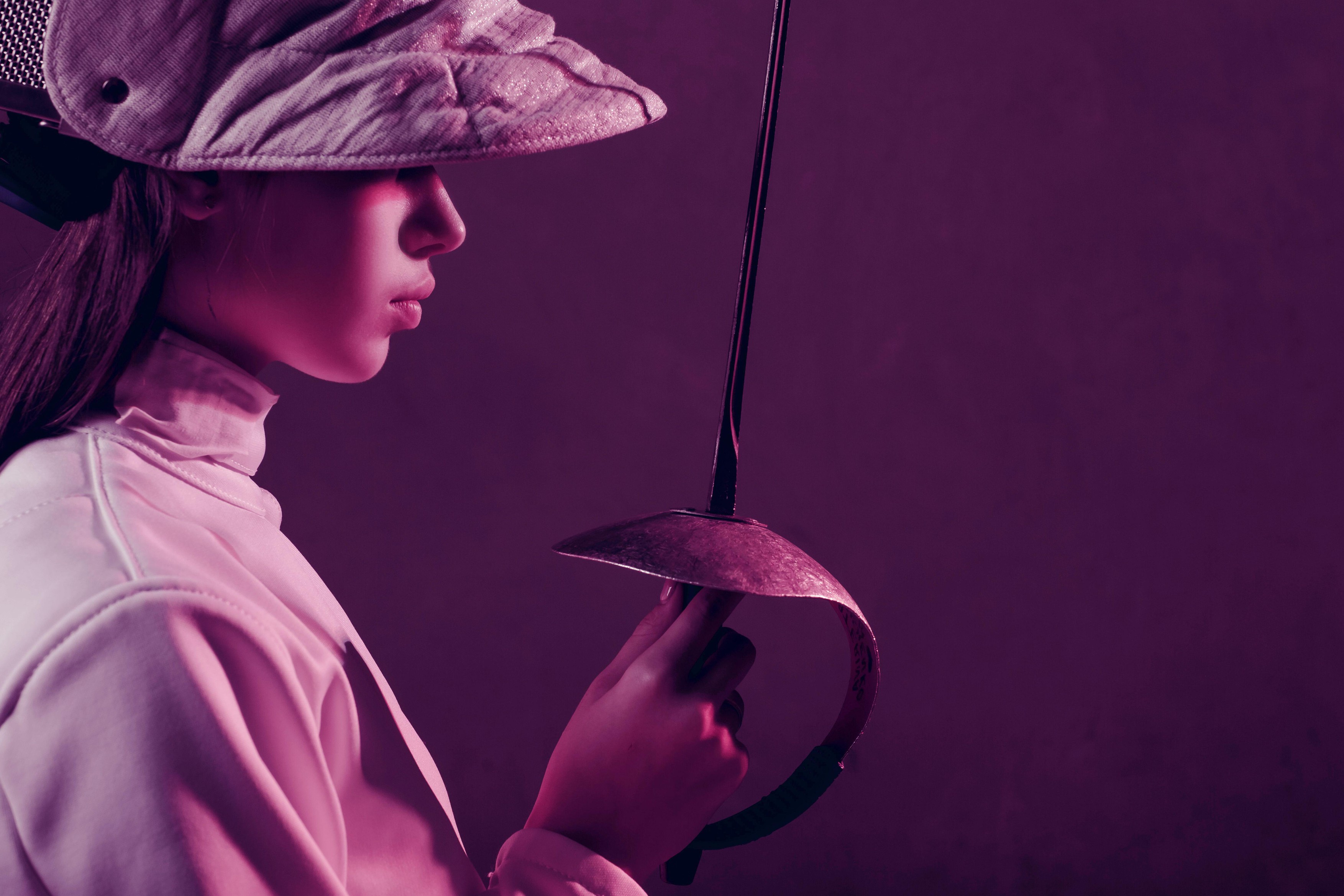 Young woman fencer profile portrait with fencing equipment and sword