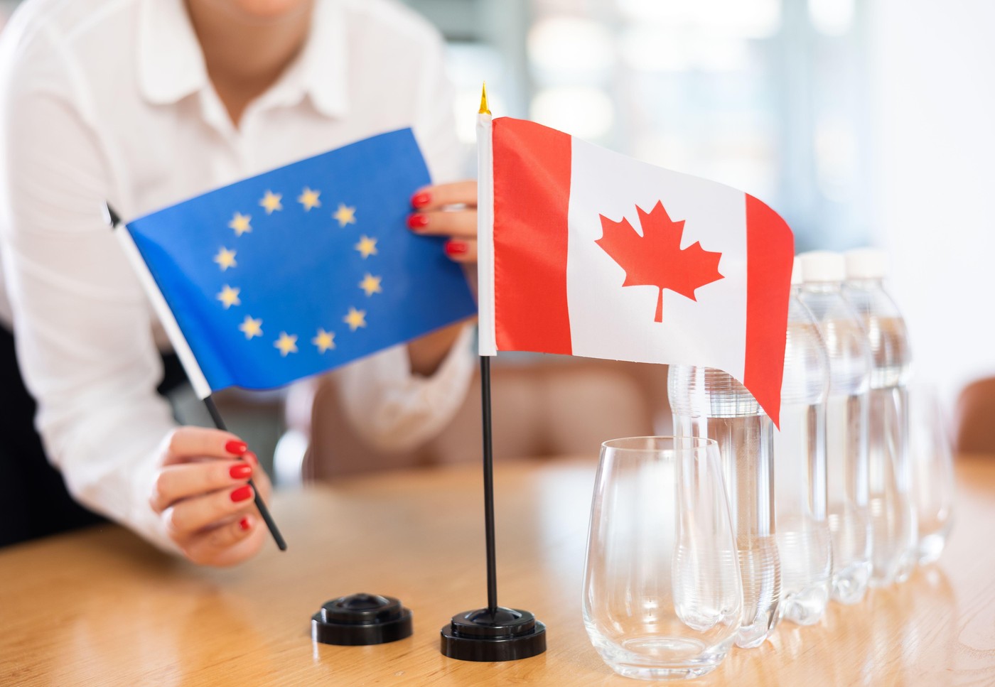 Unrecognizable girl sets midget flags of Canada and European Union before international negotiations