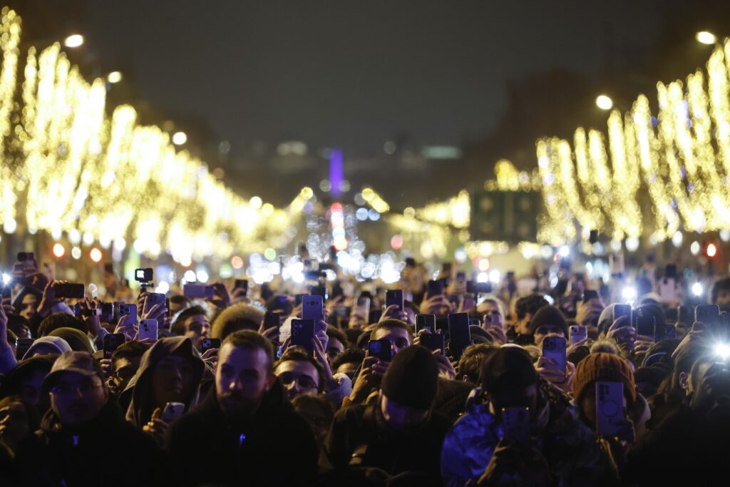 epaselect epa11800534 Thousands of spectators stand on the Champs Elysee as fireworks illuminate the sky over the The Arc of Triomphe during the New Year's celebrations in Paris, France, 01 January 2025.  EPA-EFE/YOAN VALAT