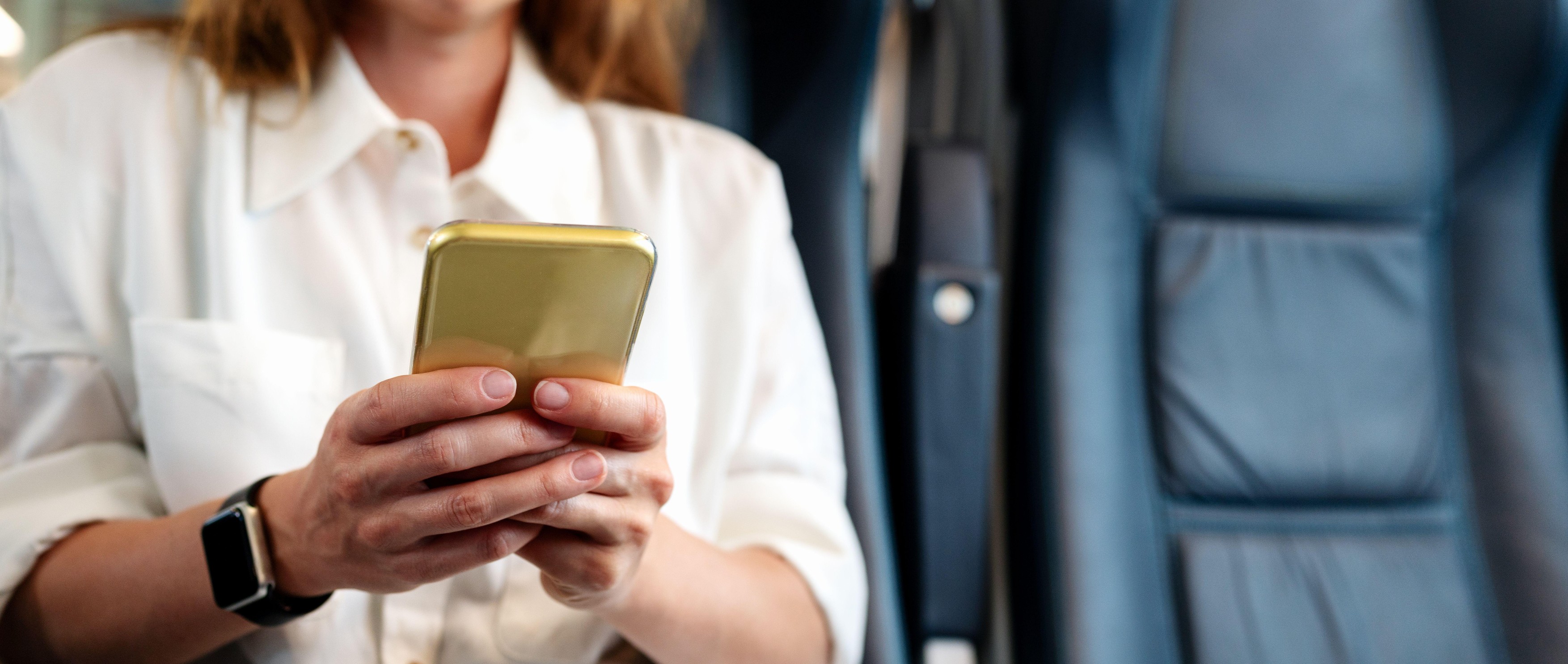 Close-up of a mobile phone in the hands of a businesswoman traveling by train.