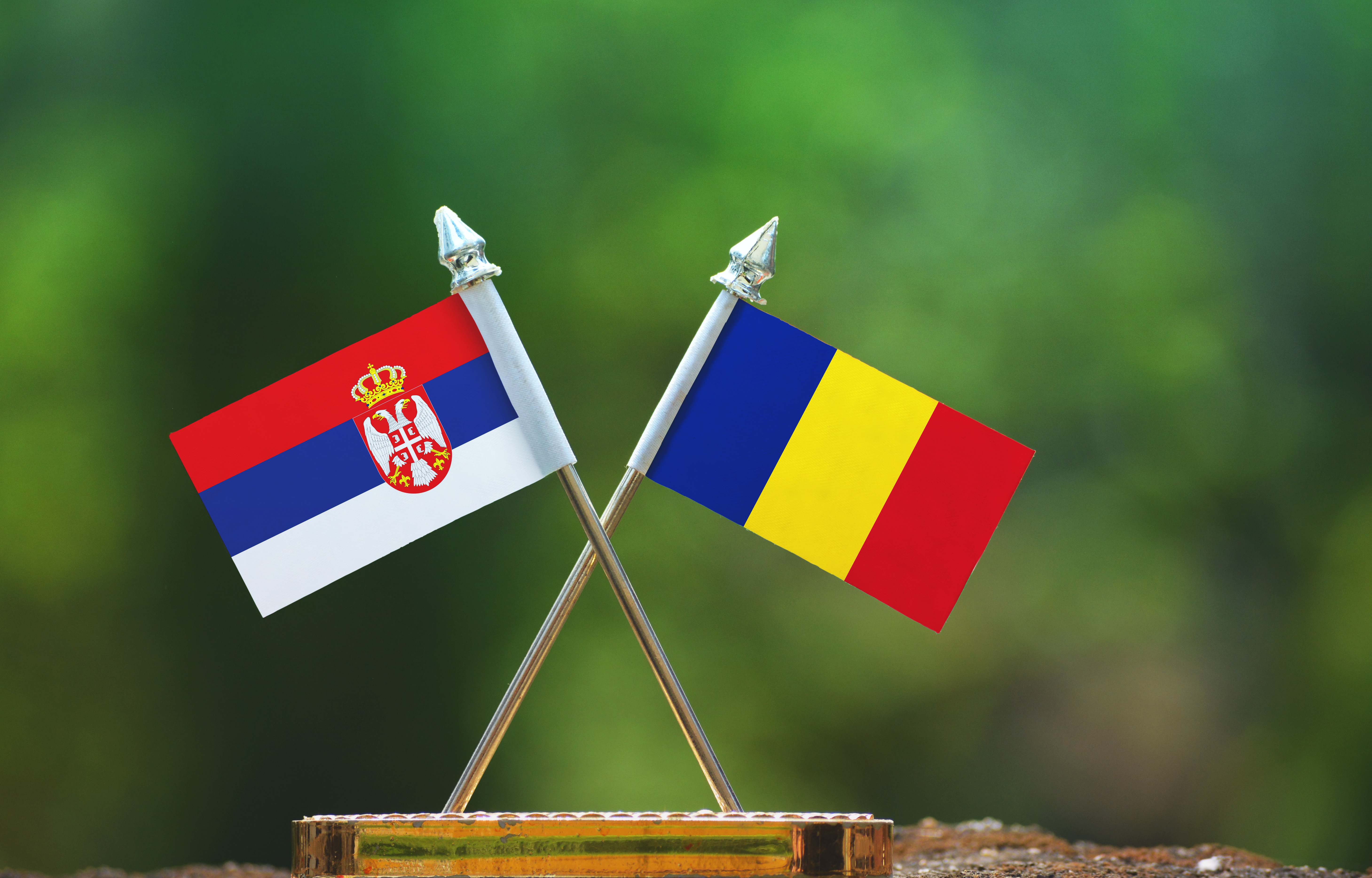 Romania,And,Serbia,Small,Flag,With,Blur,Green,Background