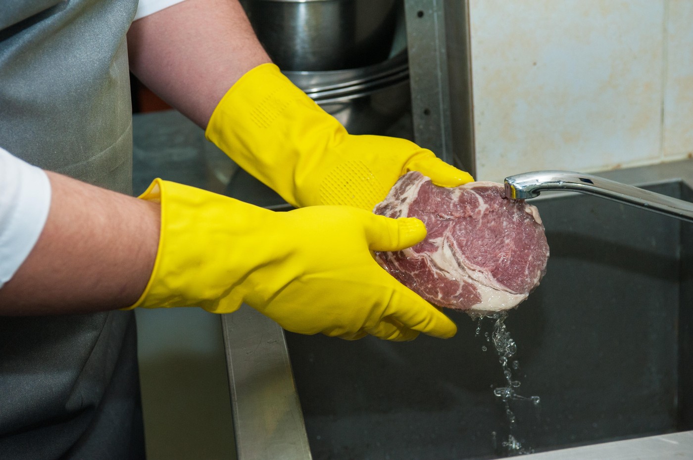 Hands in gloves washing and cleaning meat at the kitchen sink,Image: 319082462, License: Rights-managed, Restrictions: , Model Release: no, Credit line: Zoonar/Ruslan Olinchuk, Zoonar GmbH / Alamy / Profimedia