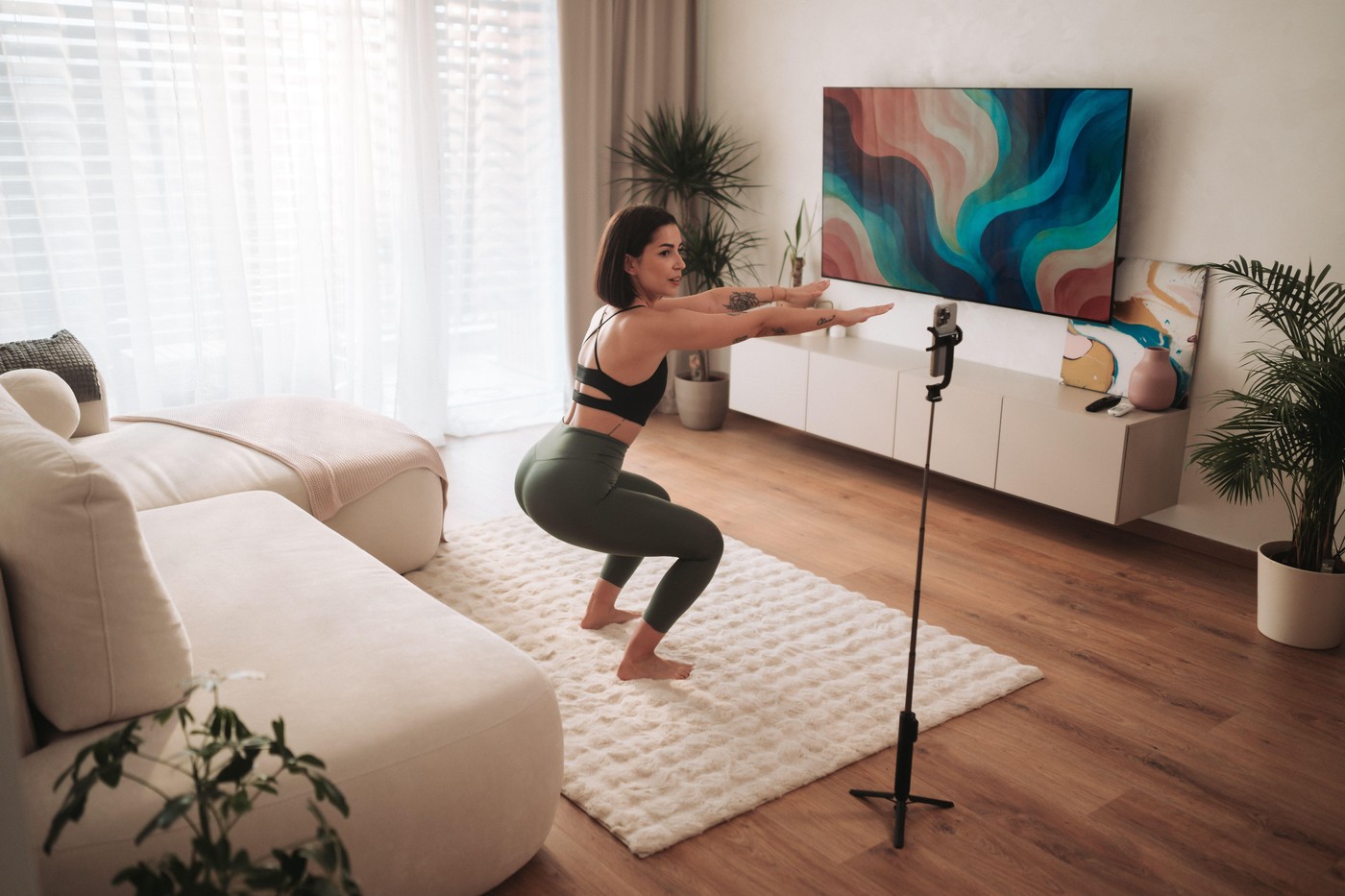 A woman is performing squats in her stylish, modern living room while exercising at home,Image: 1017406573, License: Royalty-free, Restrictions: , Model Release: no, Credit line: Big Shot Theory / Alamy / Profimedia