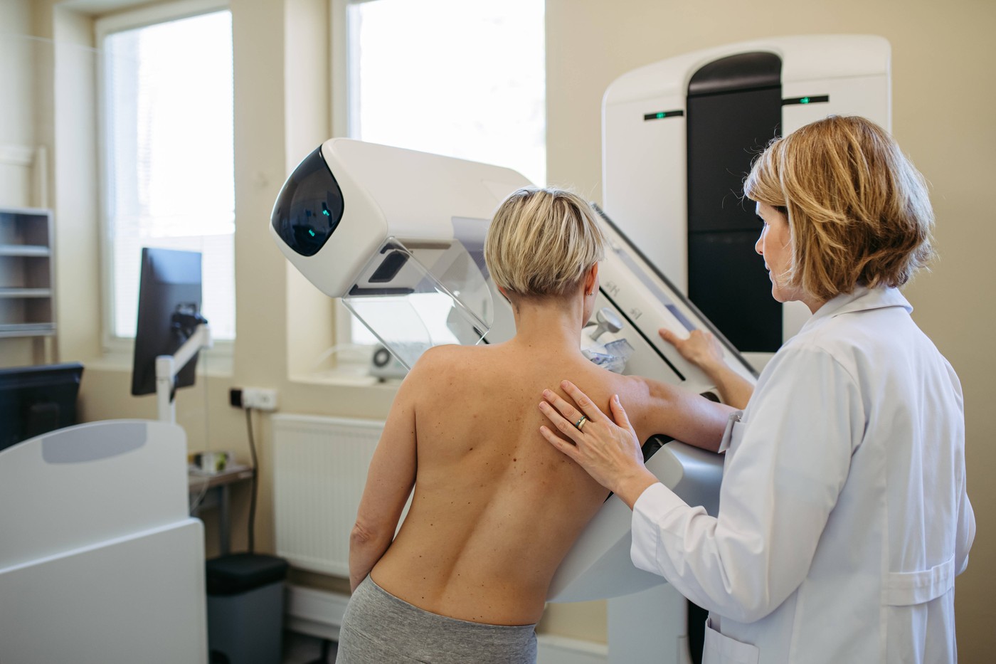 Healthcare professional adjusts the patient for proper mammogram.