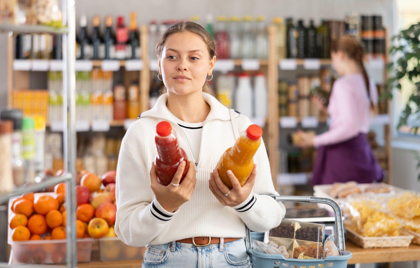 woman chooses juices against the background of buyers