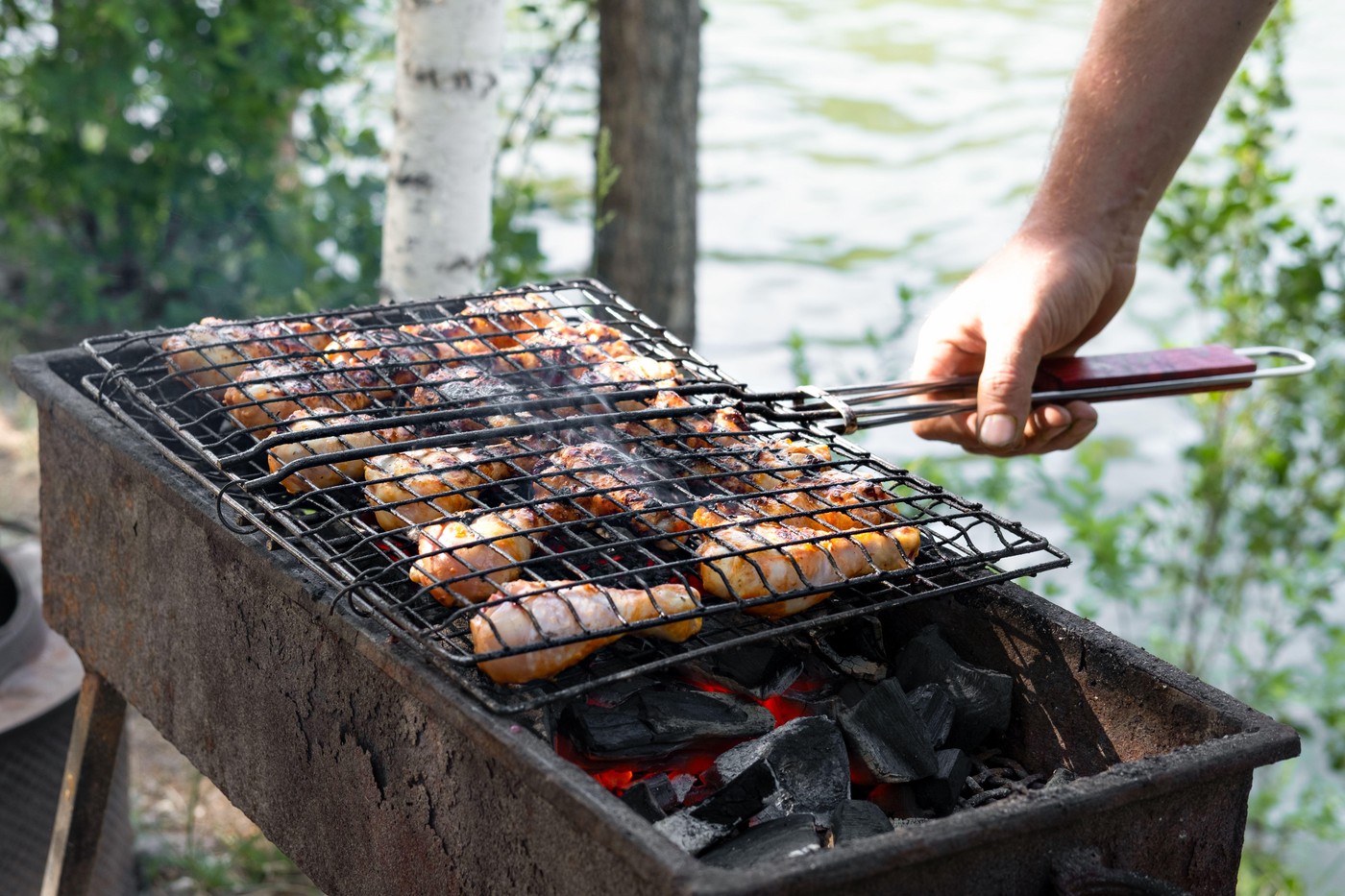 man's hand frying chicken legs.