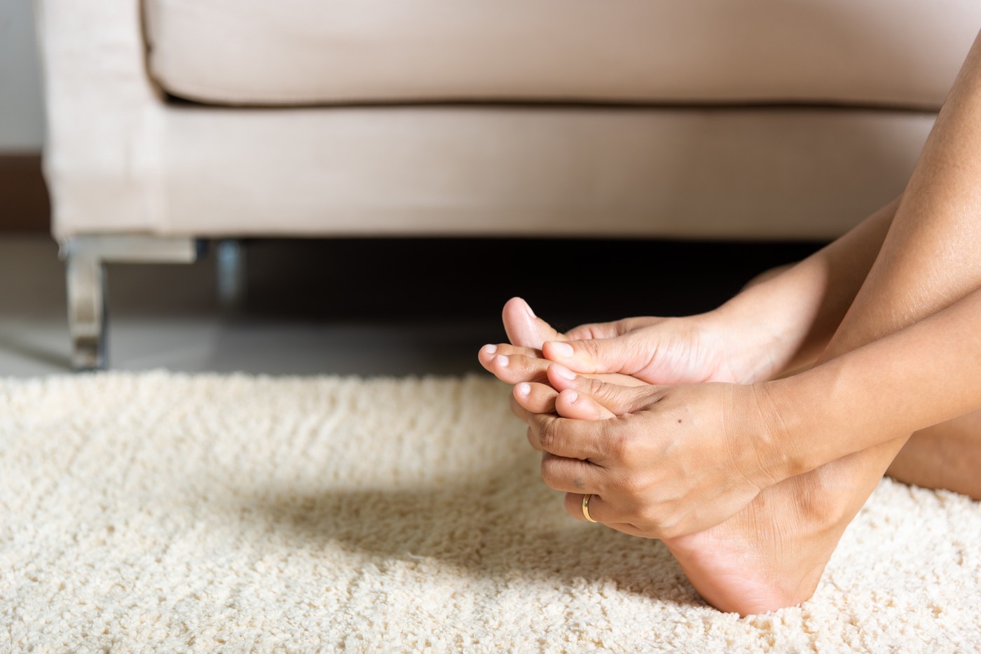 Asian woman holds her toe injury feeling pain her foot at home