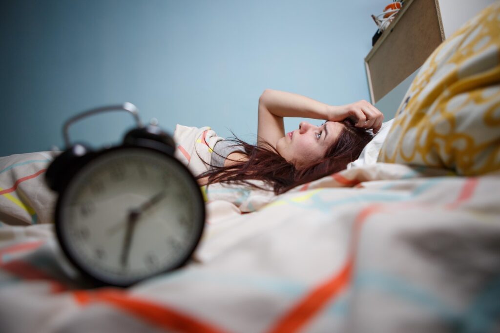 Woman with insomnia touching her head with defocused alarm-clock on foreground.,Image: 280402759, License: Royalty-free, Restrictions: , Model Release: yes, Credit line: Sergey Mironov / Alamy / Alamy / Profimedia