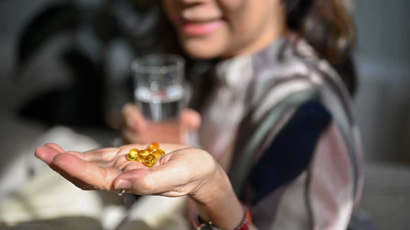 Close-up image, A vitamin pills, omega 3 fish oil pills on an aged woman hand with blurred background. Healthy lifestyle and nutrition, healthcare.