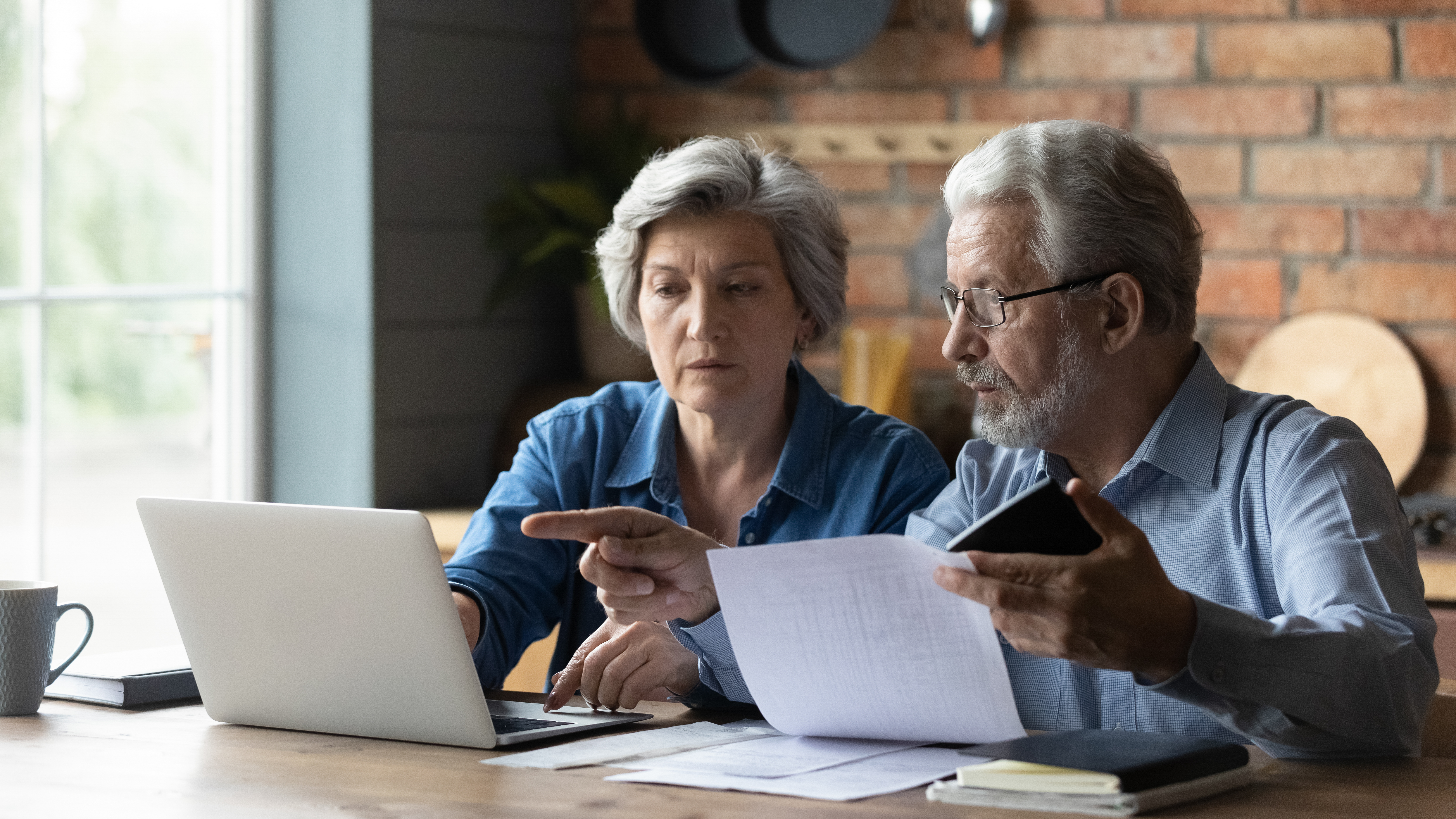 Focused,Senior,Husband,And,Wife,Sit,At,Table,At,Home
