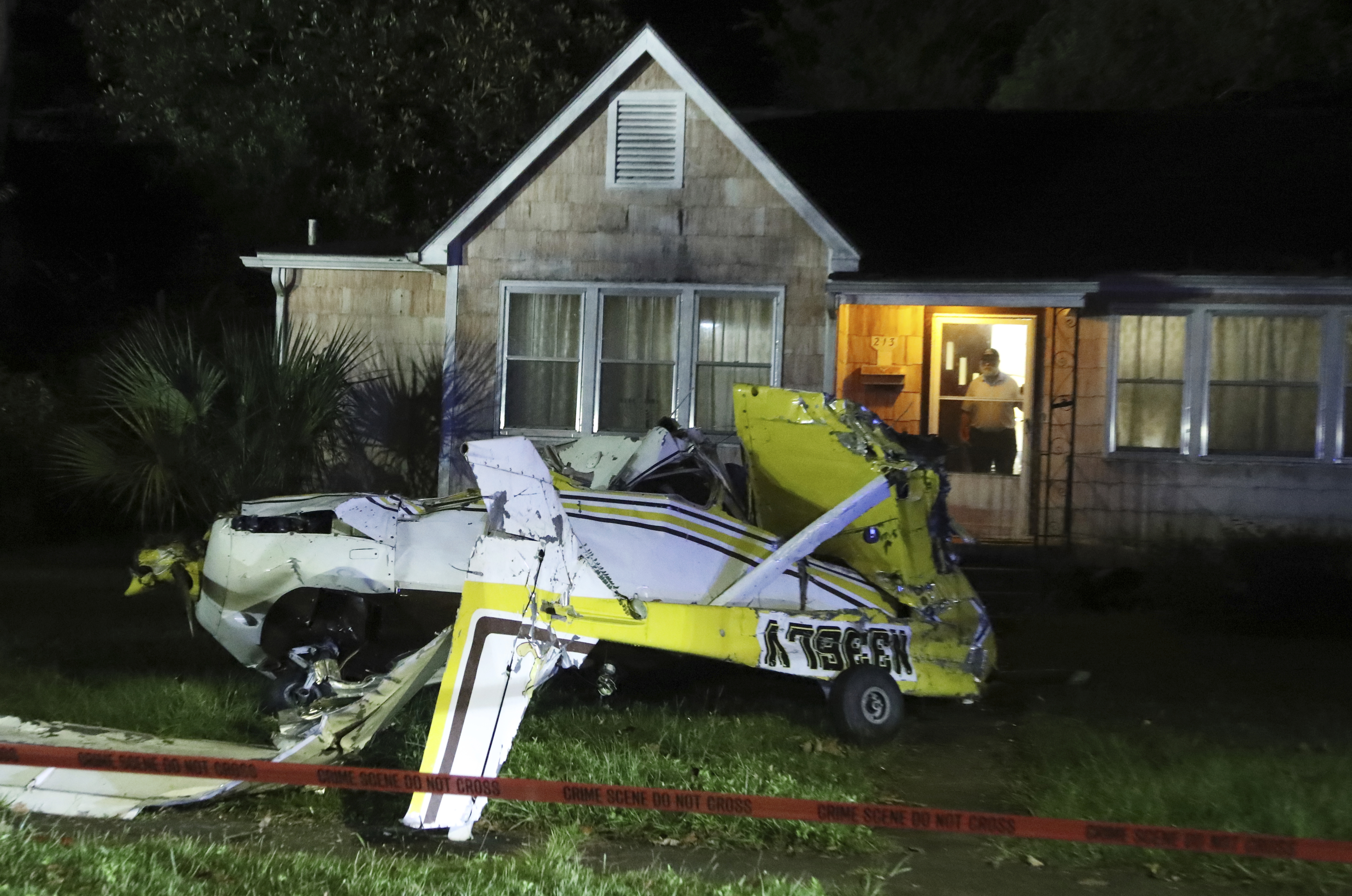 A man looks out the front door of his home after a Cessna crashed in the front yard in Savannah, Ga., Sunday, Oct. 13, 2024. (Richard Burkhart/Savannah Morning News via AP)