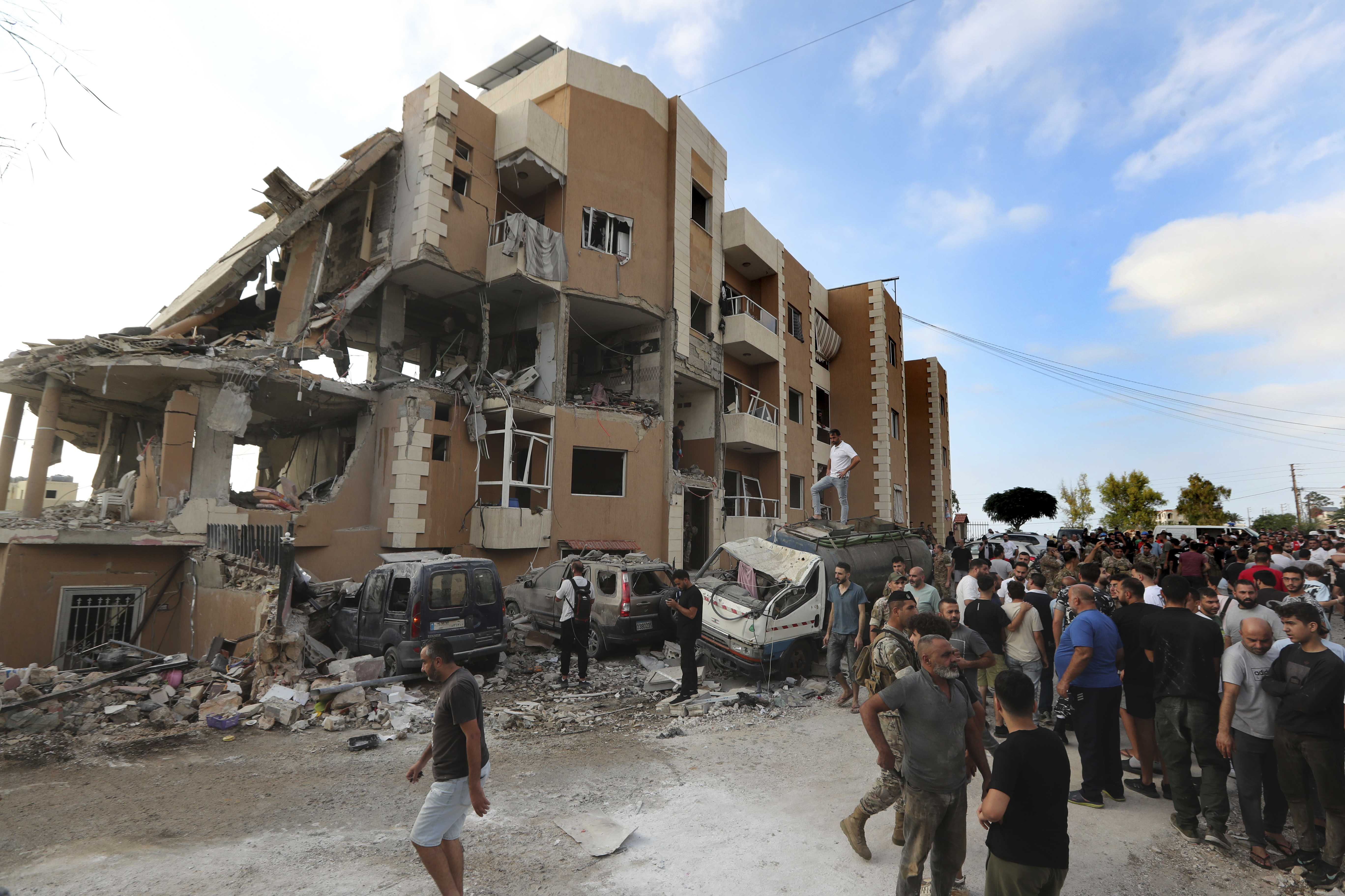 People gather next of a destroyed building hit by an Israeli airstrike, in Barja village, south of Beirut, Lebanon, Saturday, Oct. 12, 2024. (AP Photo/Mohammed Zaatari)