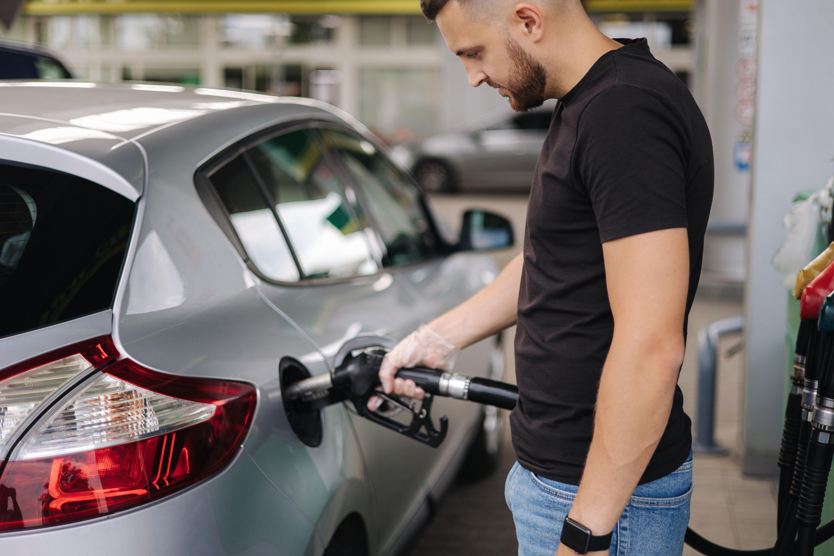 Man is refueling at gas station. Male hand filling benzine gasoline fuel in car using a fuel nozzle. Petrol concept