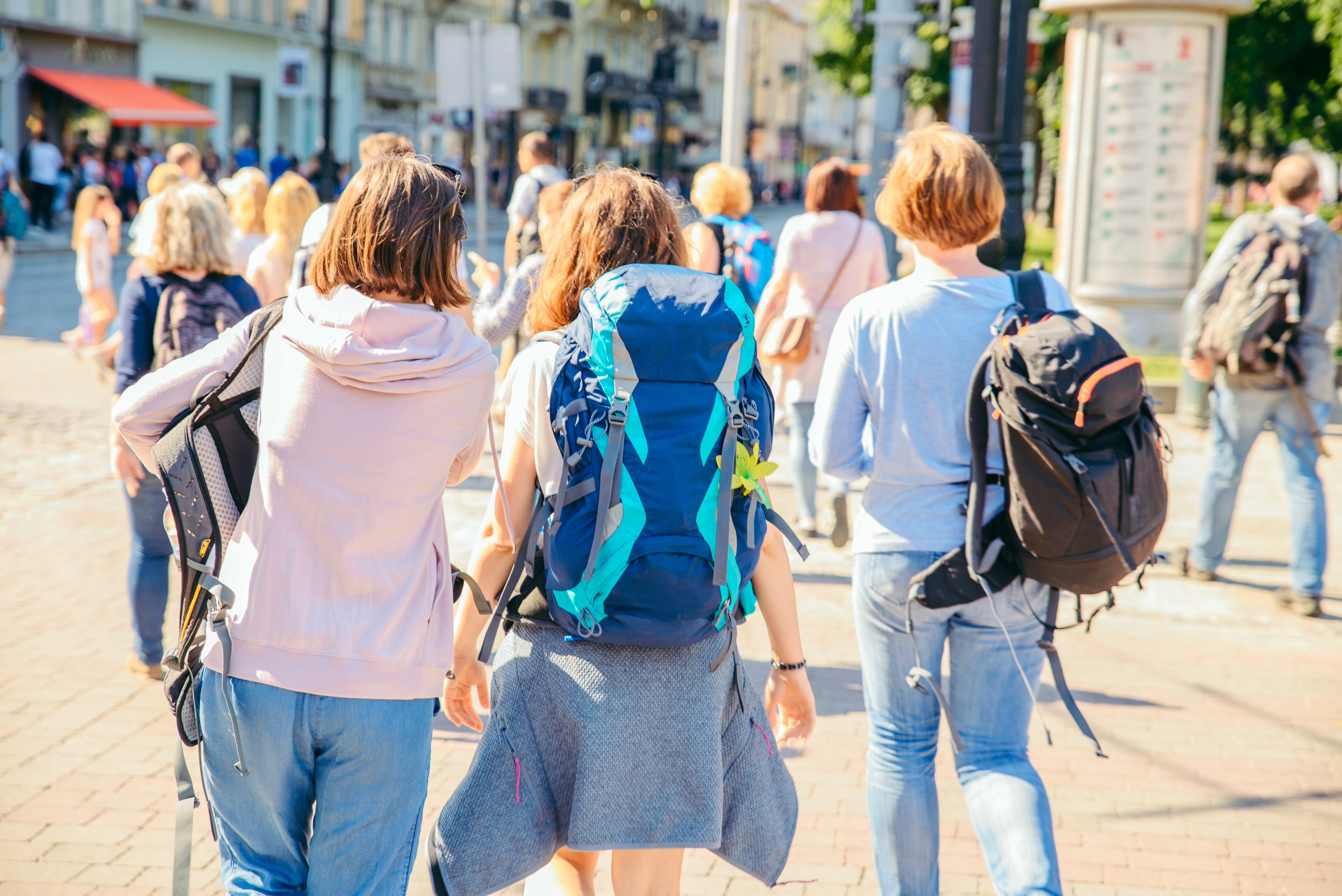 Three,Young,Adult,Women,Walking,By,City,Streets,With,Backpack.
