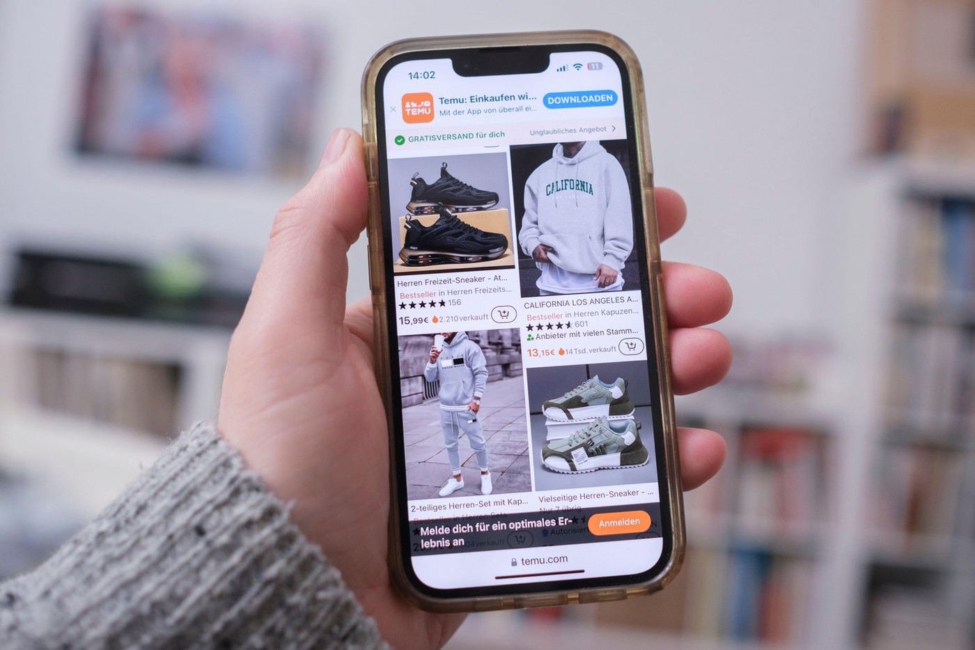 Hand holding a mobile phone showing the website of the Chinese company Temu