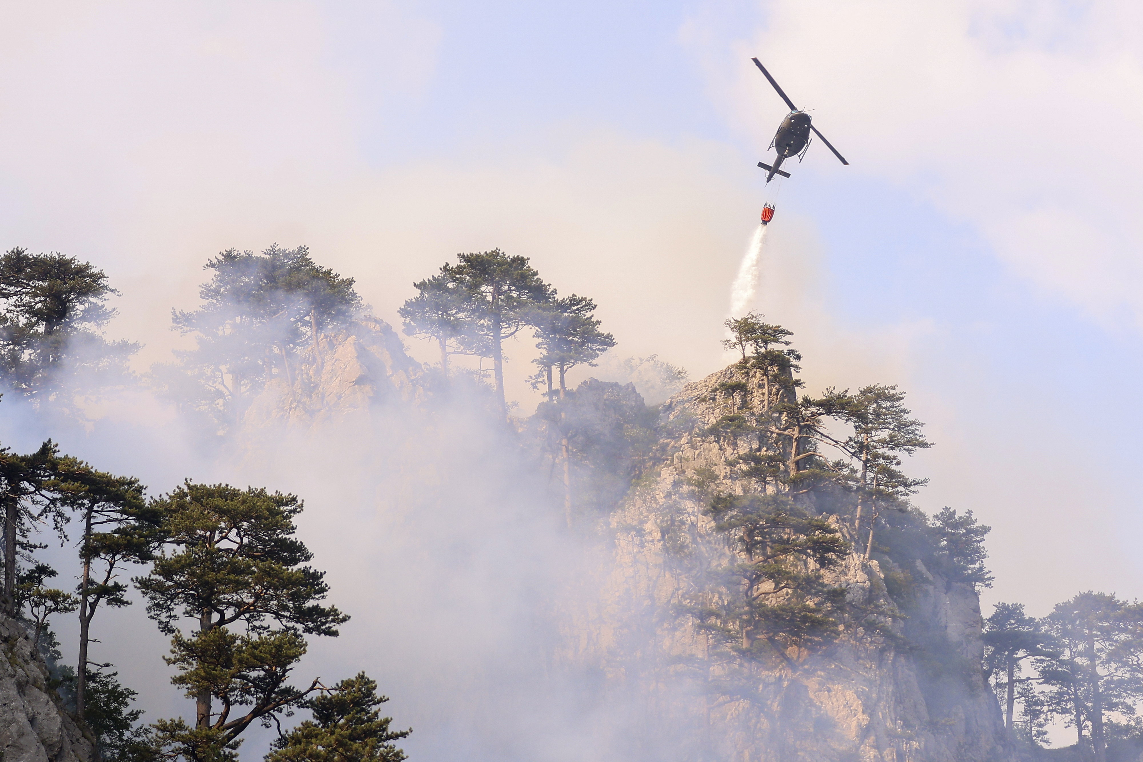 A helicopter drops water over a fire in Tjentiste, Bosnia, Tuesday, Aug. 13, 2024. Five helicopters are extinguishing fire at Sutjeska National Park, where a centuries-old conifer forest is burning. (AP Photo/Armin Durgut)