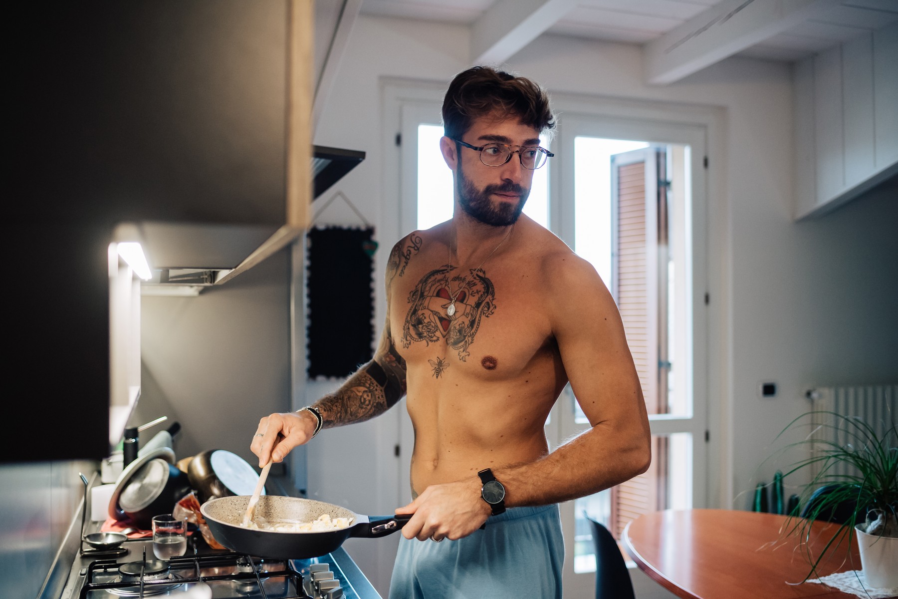 Mid adult man with tattoos cooking breakfast in frying pan