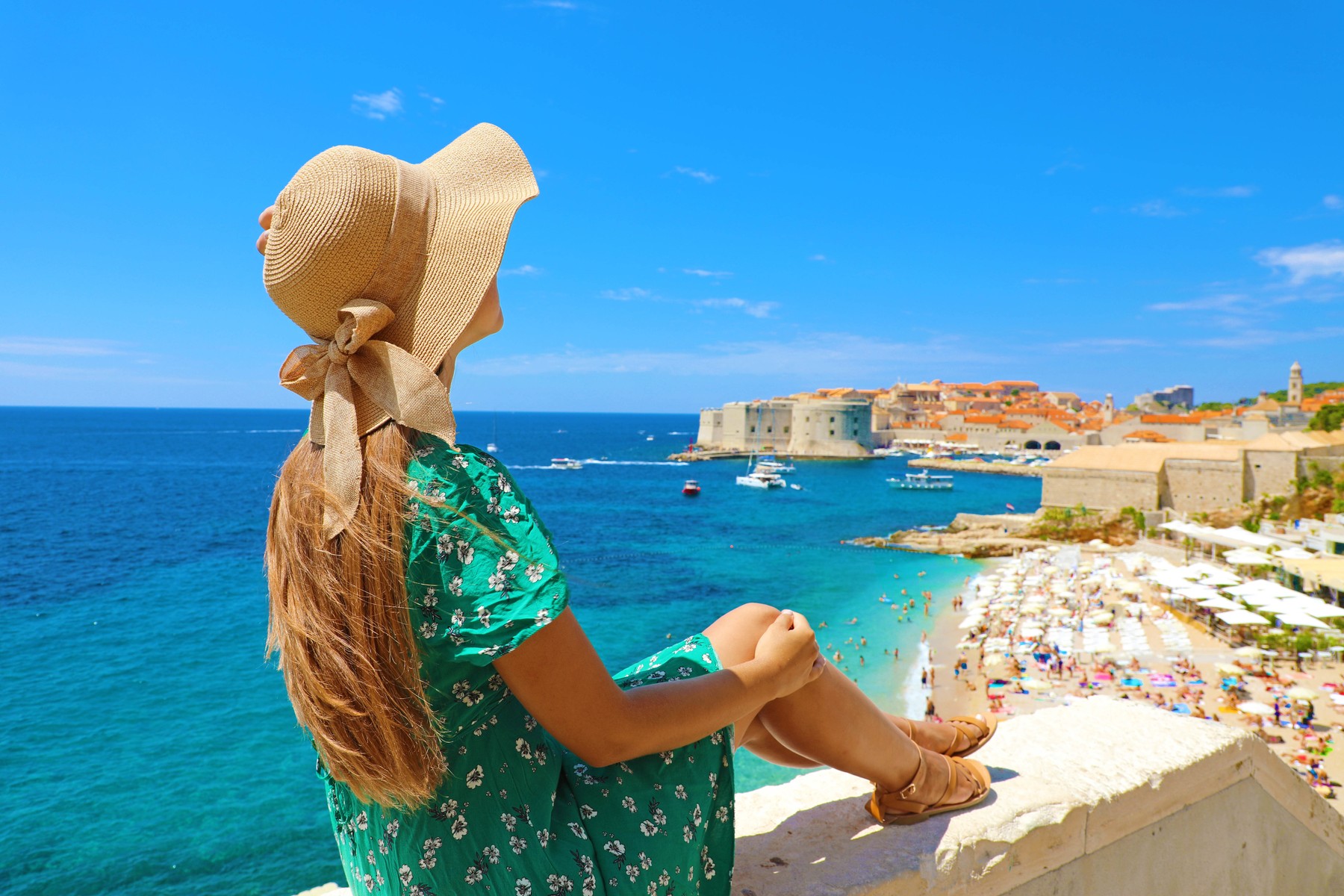 Beautiful young woman with hat sitting on wall looking at stunning panoramic village of Dubrovnik in Croatia,  Europe,Image: 528944705, License: Royalty-free, Restrictions: , Model Release: yes, Credit line: Sergio Monti / Panthermedia / Profimedia